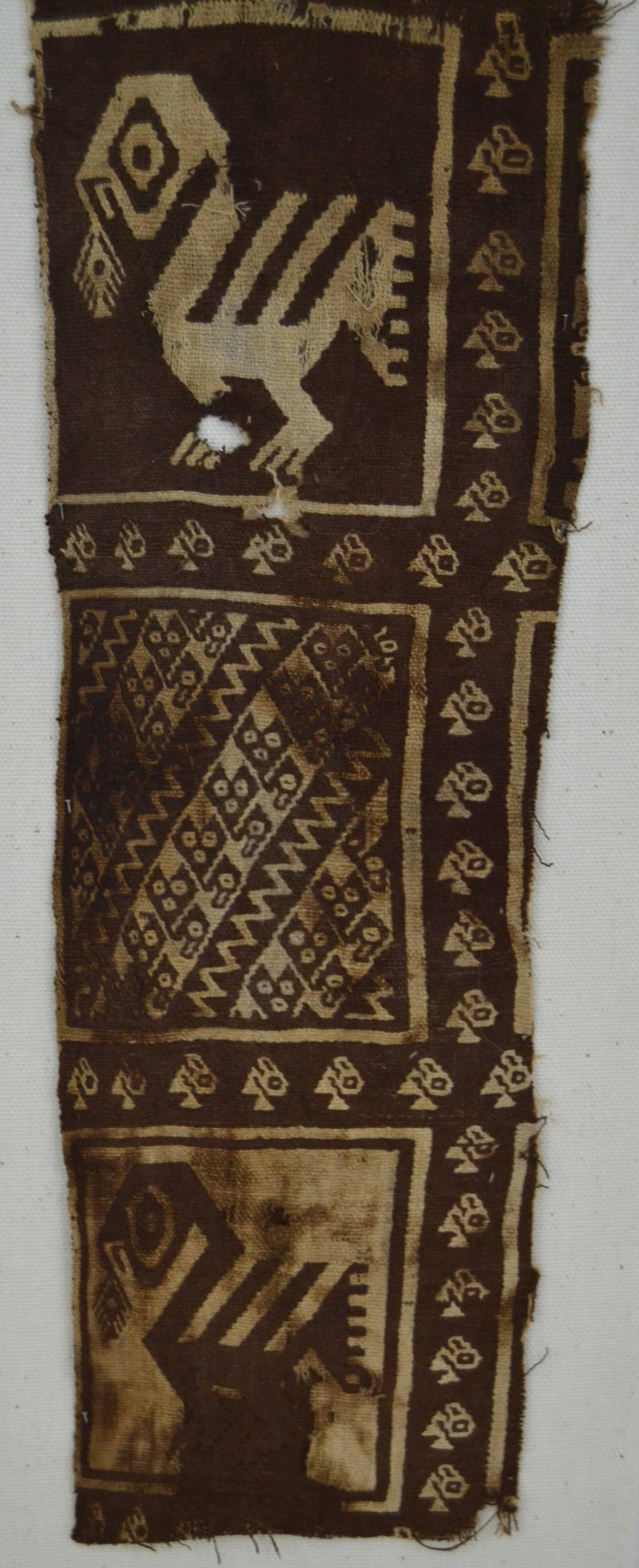 Brown and natural woven (cotton) textile fragment depicting birds and feline figures, Chimu culture, fragment size 17" x 4.5", mounted and pinned on linen.