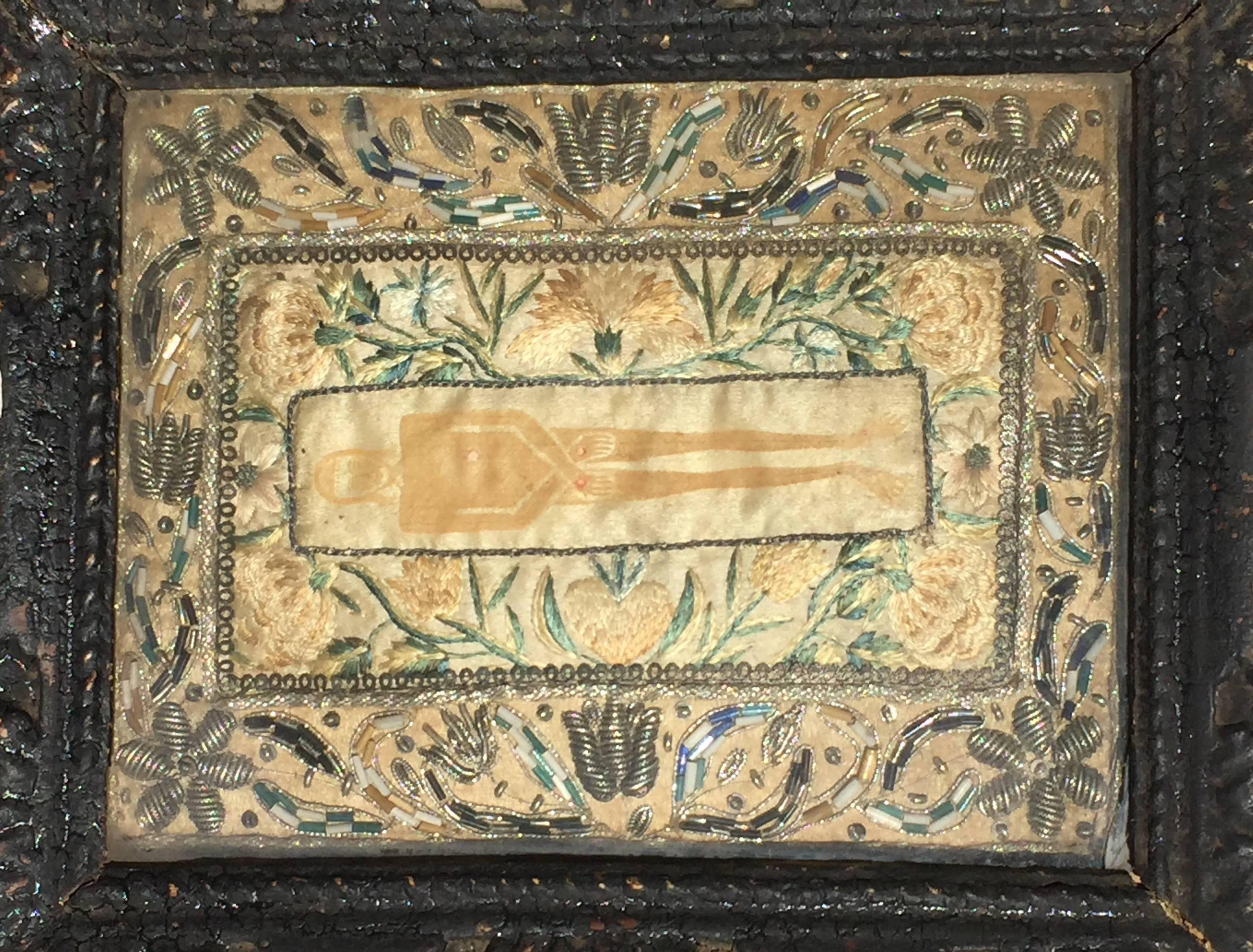 A late 18th century French devotional embroidery depicting the Shroud of Besançon, which was a replica of the Shroud of Turin destroyed in the French revolution. Colored silk and metallic thread embroidery with beadwork. Central stenciled/painted