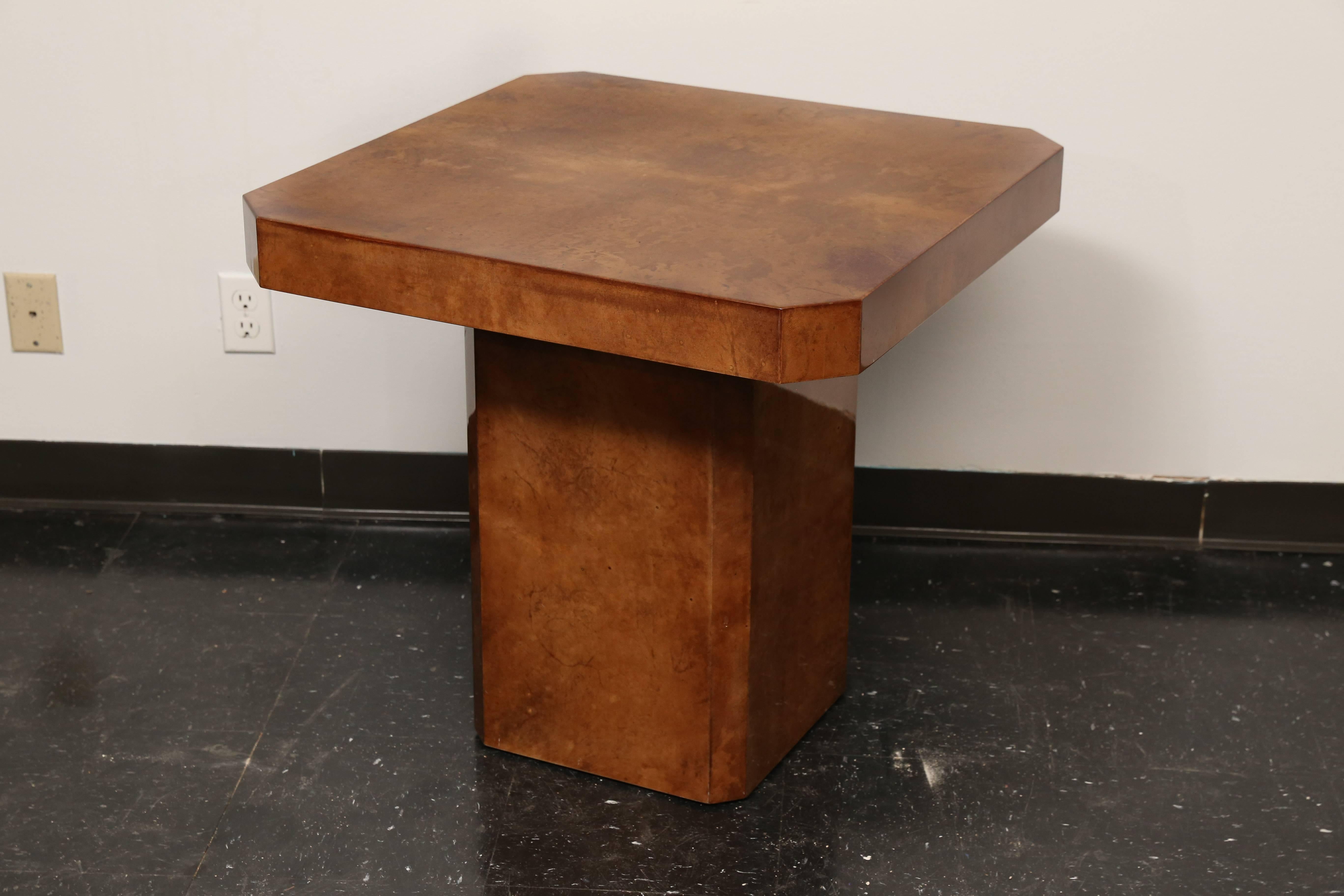 Mid-Century lacquered goatskin side table in the manner of Karl Springer with beautiful patina on a single rectangular pedestal base. Corners of tabletop styled with cut mitered corners. Patina is a rich dark caramel color with variation of color