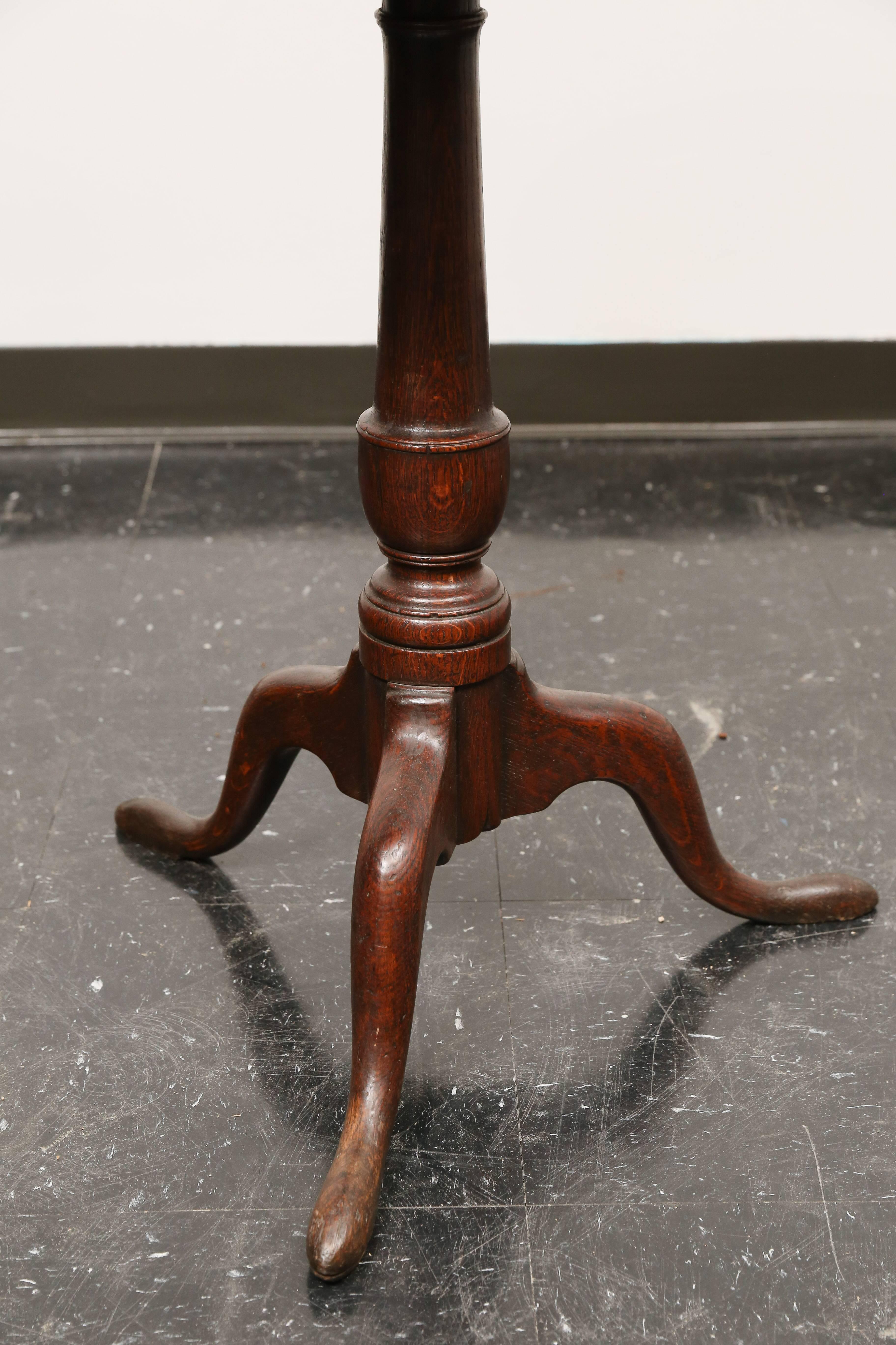 19th century English Georgian oak tilt top table with original iron hardware on tripod pad feet. Centre column in the simple shape of a urn with several turned rings details. Beautiful patina.