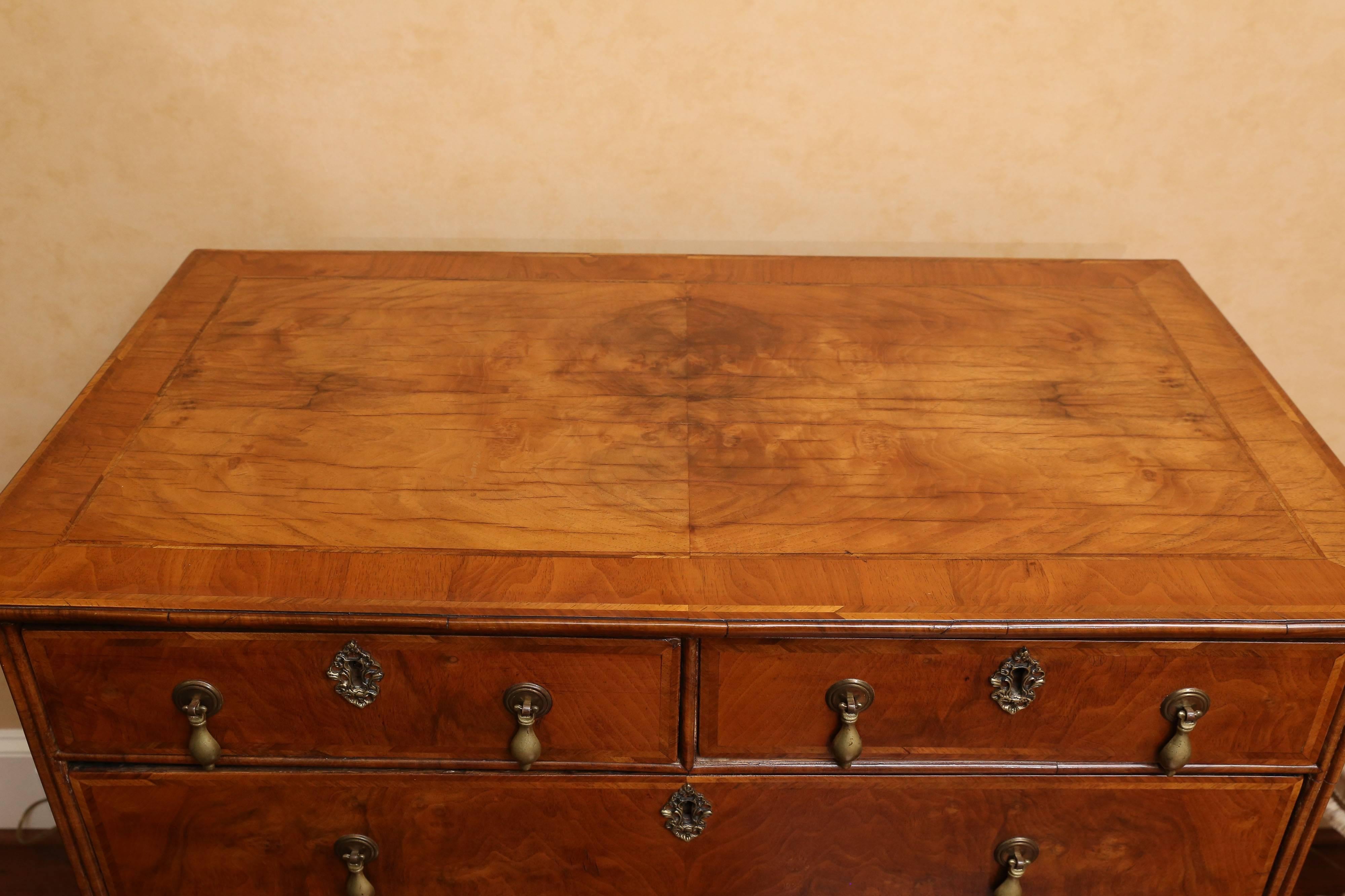 18th century William and Mary walnut chest with two small top drawers and three larger drawers beneath. The chest has burl walnut veneer on its top and the facade of its drawers along with crossbanding details. It sits on bun feet. The inside of the