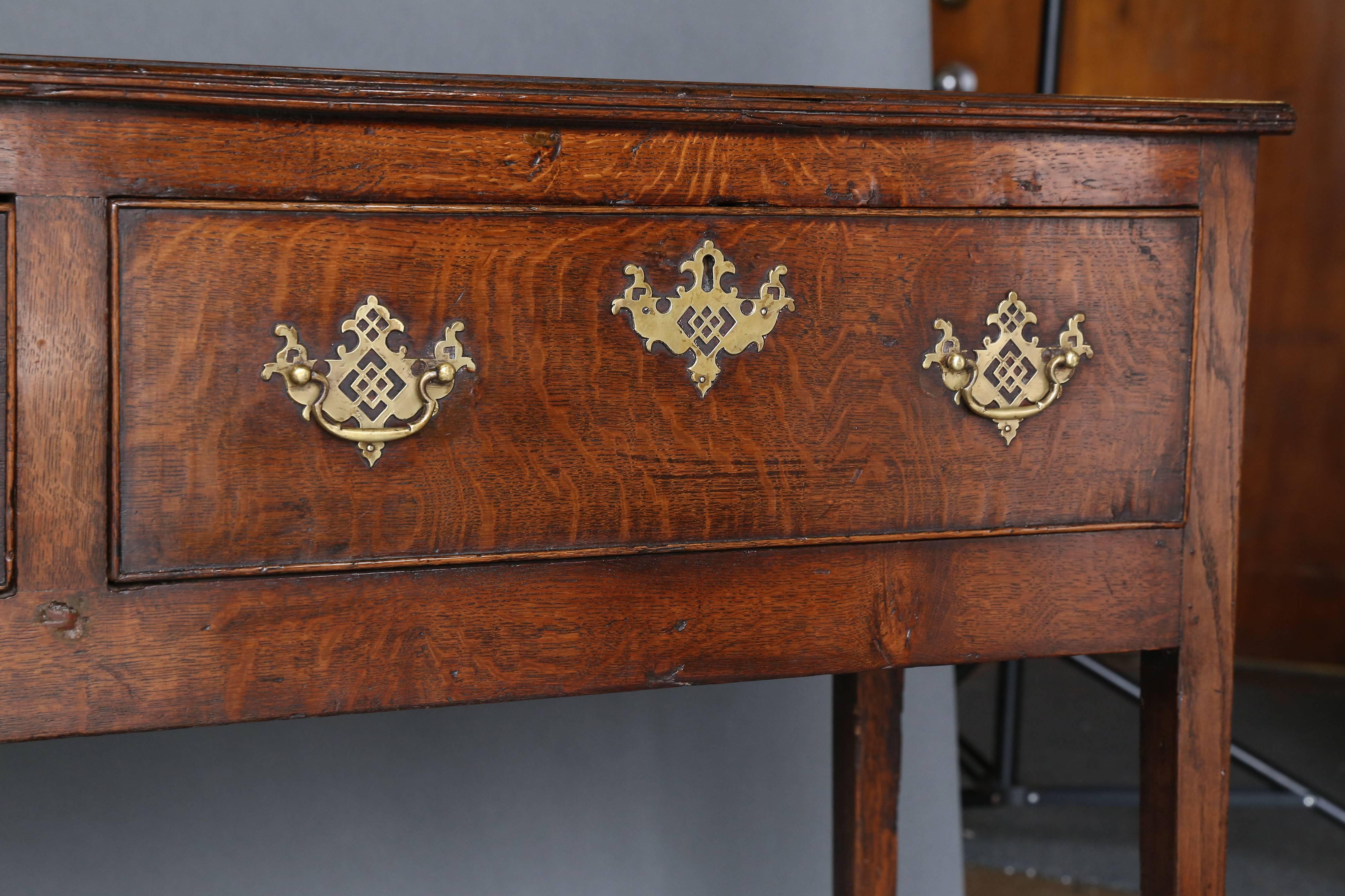 18th century oak dresser base, the long rectangular top three oak lined deep drawers to the frieze with brass plate handles, raised on square tapering legs. Beautiful patina, circa 1770.
Measures: 84