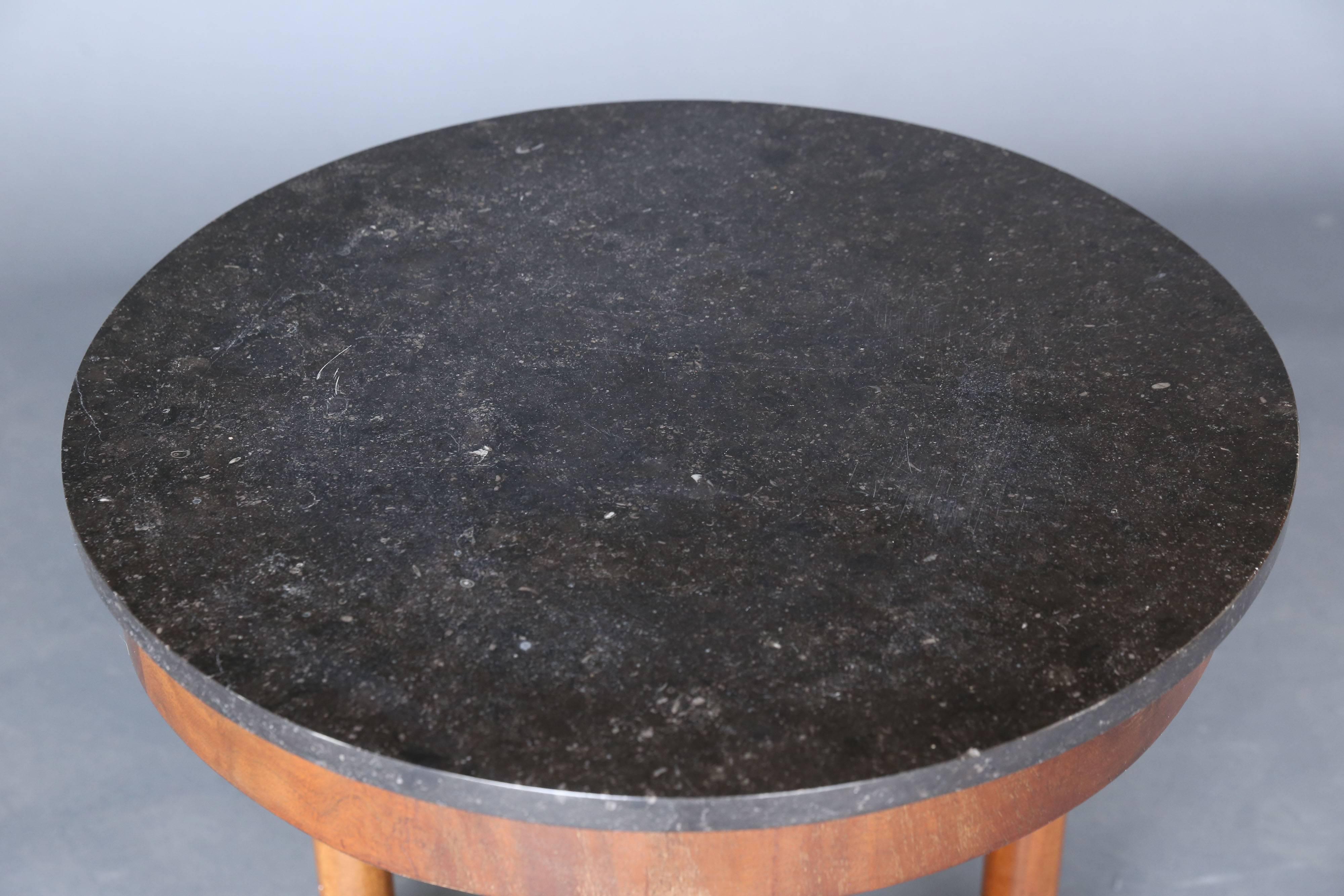 19th century marble table with a mahogany base on three legs with metal details. Legs finish off into a thick platform and then continue underneath in a similar cylindrical form.