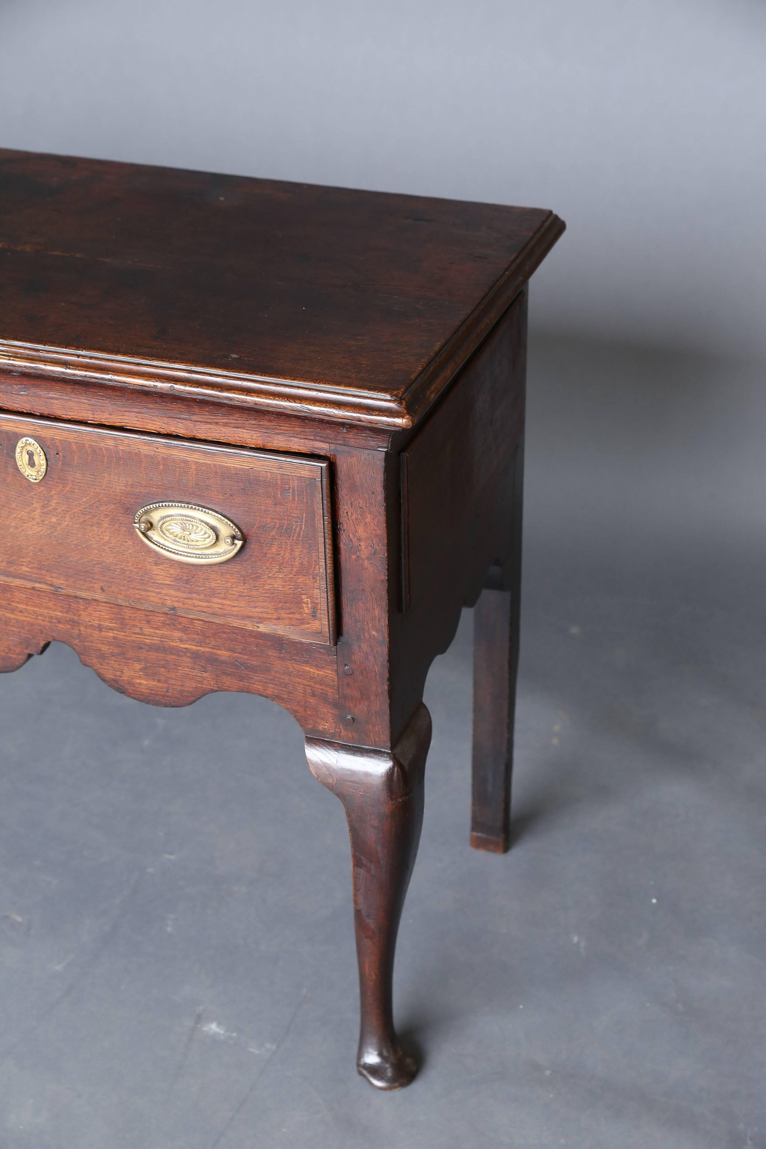 A good example of an 18th century oak serving dresser base with shaped apron standing on four cabriole legs. This three-drawer server is of good proportions and a lovely warm and rich color. This antique was produced in 1750. At the time that this