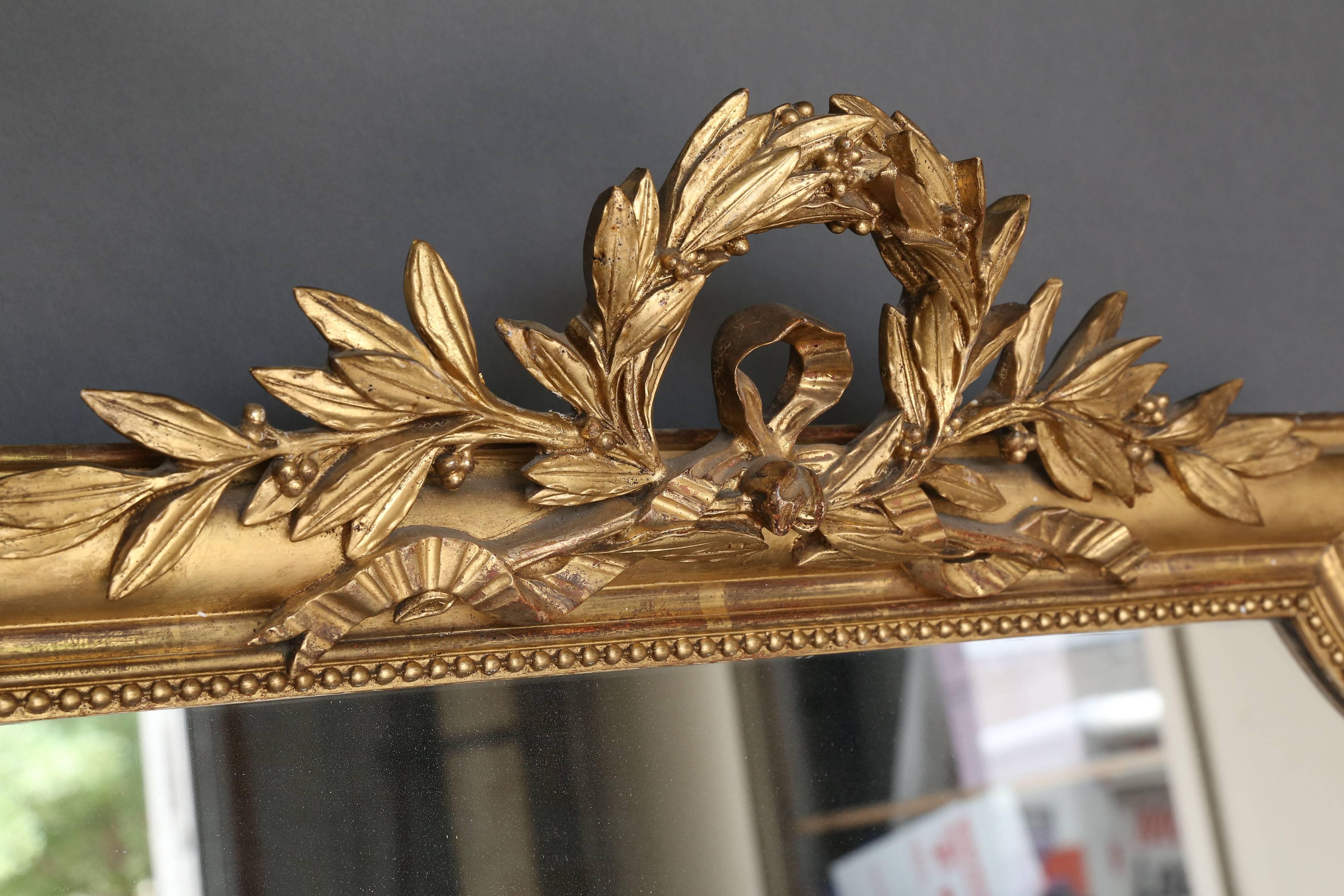 Large 19th century Directoire gilt mirror with crest of Laurel leaf couronne. Beautiful detail of pearl perimeter on the inside of gilt frame. Original mercury glass. Great patina, circa 1860.
