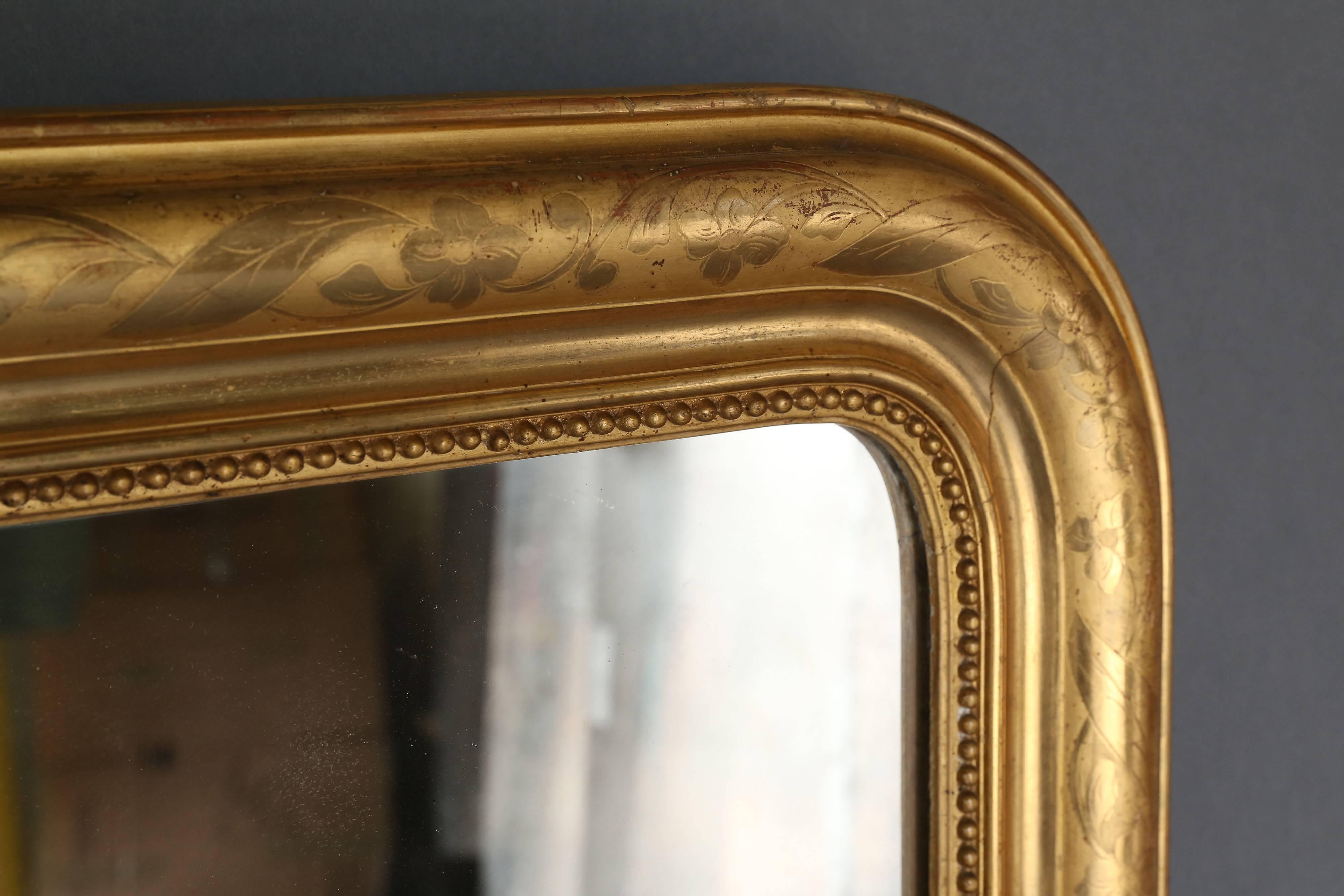 19th century Louis Philippe gilt mirror with pearl detail along the inside perimeter. Gilt is etched with a floral design that meanders along the perimeter. Original mercury glass.