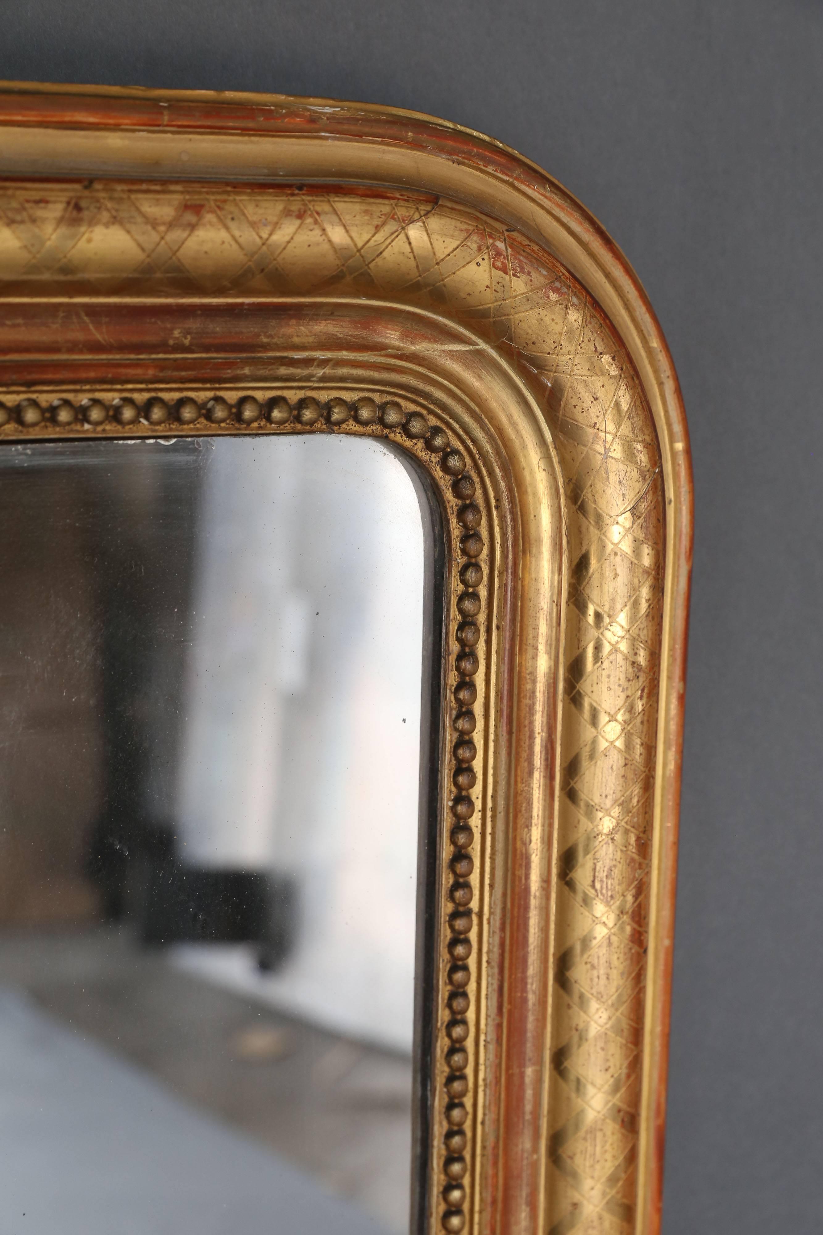 19th century Louis Philippe gilt mirror with pearl detail inside perimeter. Rounded corners on top and squared corners at the bottom. Architectural criss-cross detail etched on the gilt perimeter. Original mercury glass mirror.