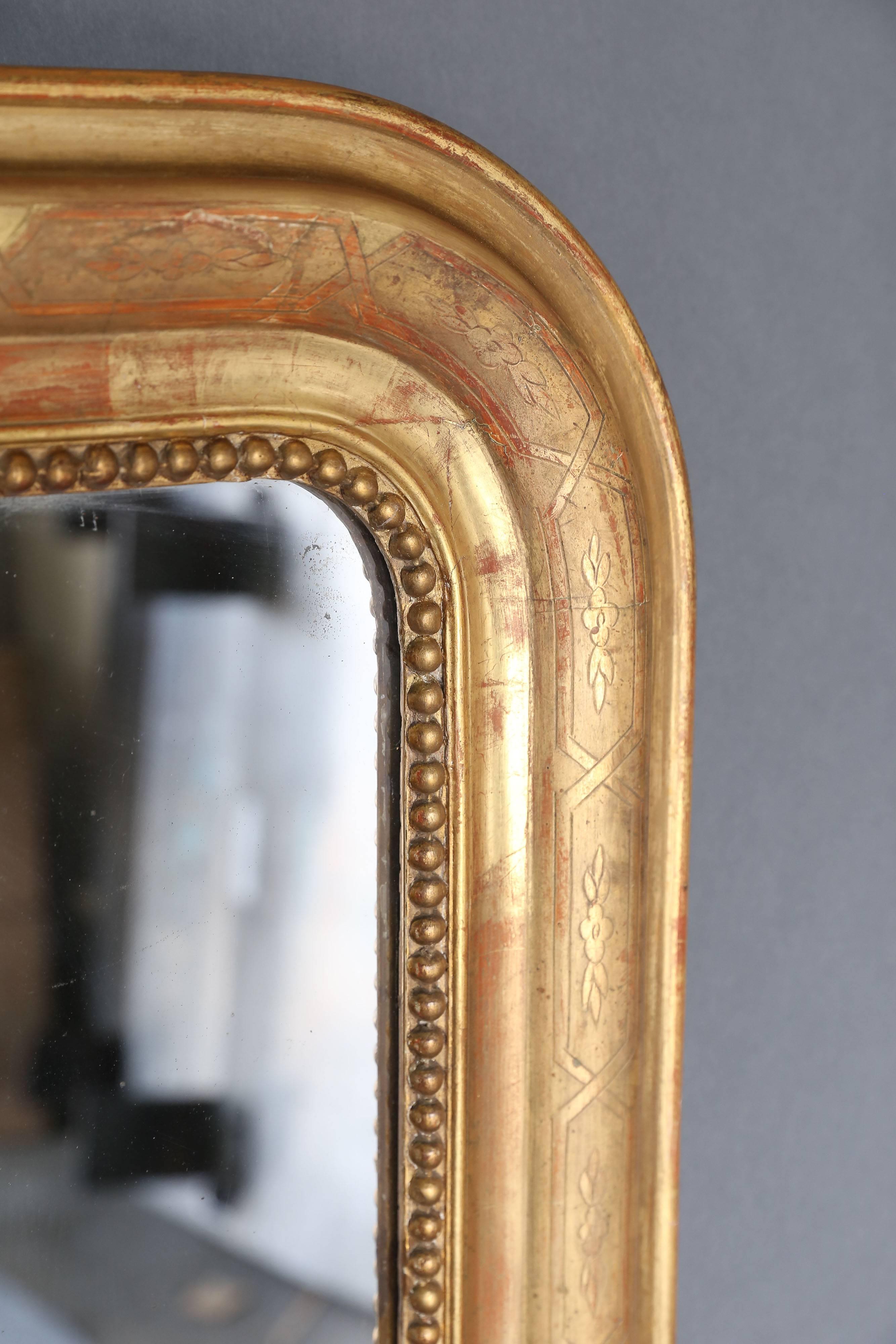 19th century Louis Philippe gilt mirror with pearl detail on the interior perimeter. Etching on gilt is an intertwining design with simple floral motifs throughout. Mercury glass is original.