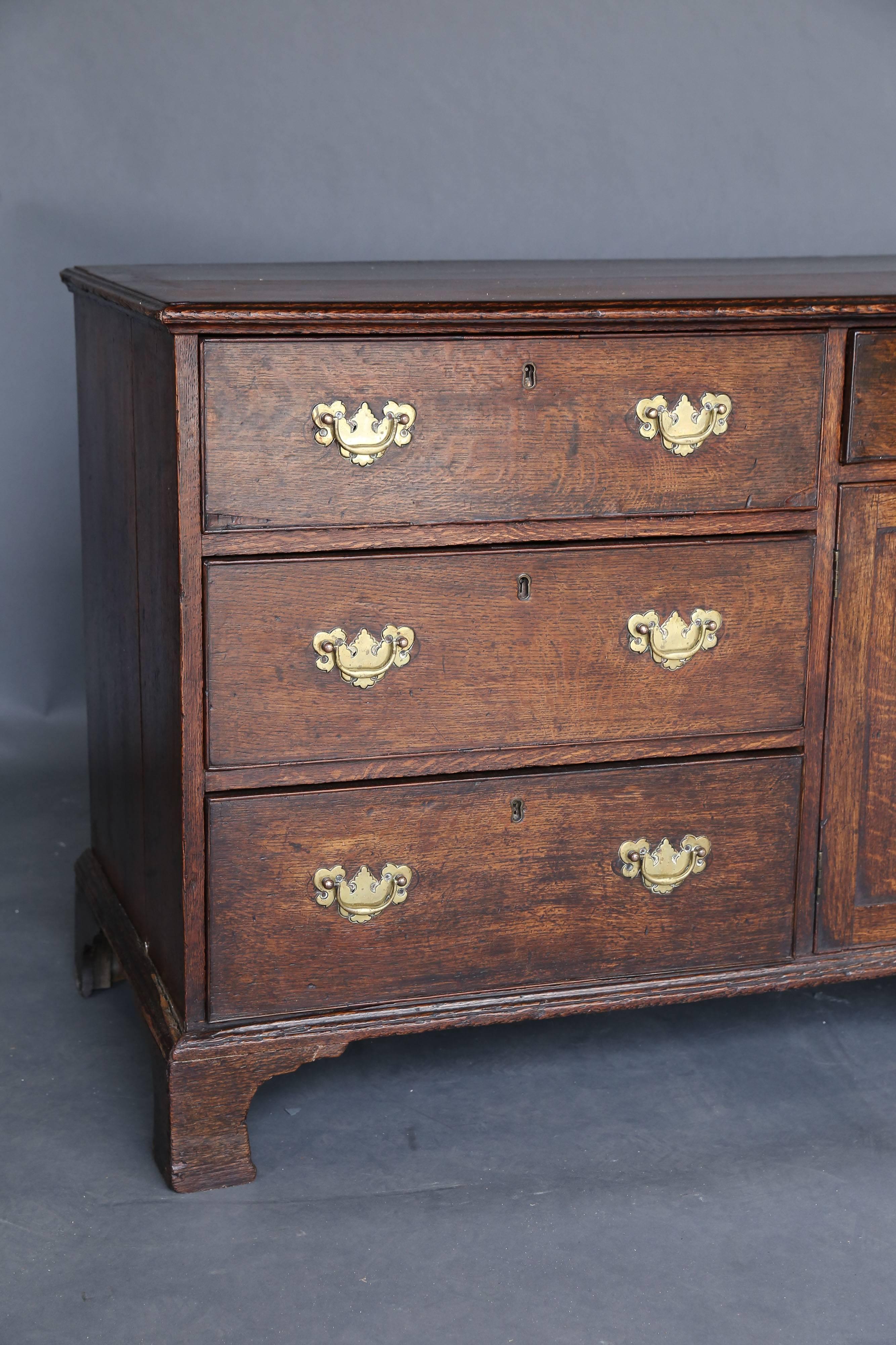 An early George III oak dresser base of superb color and proportions. Seven drawers and a two-door cabinet. Bracket feet at ends and one in the center, circa 1760.
