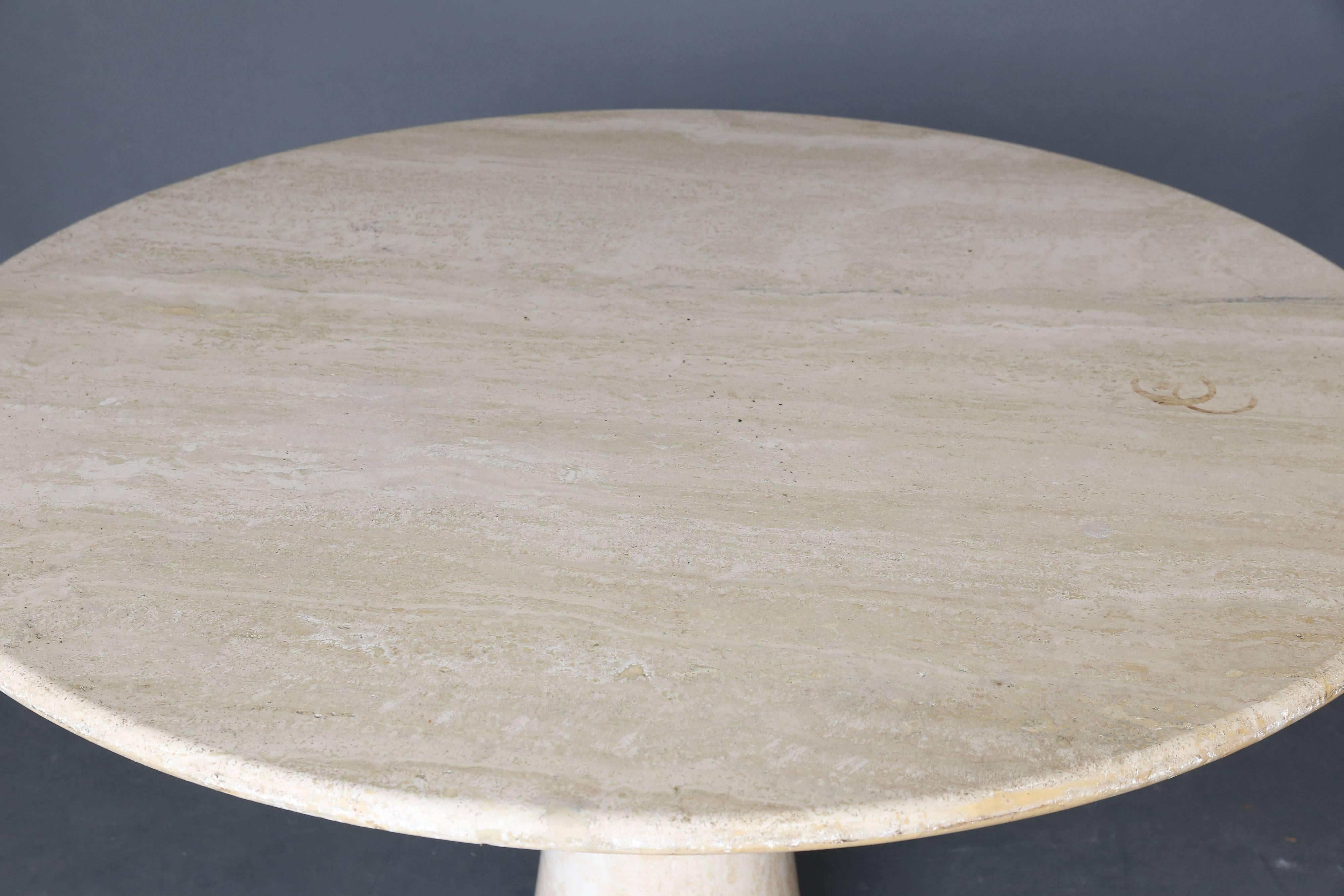 Travertine dining table. Table is comprised of two pieces a cone shaped slightly hourglass base and a circular top. Measures: Diameter 52 inches; Can easily seat 6 people. Beautiful lines and patina, circa 1980s.