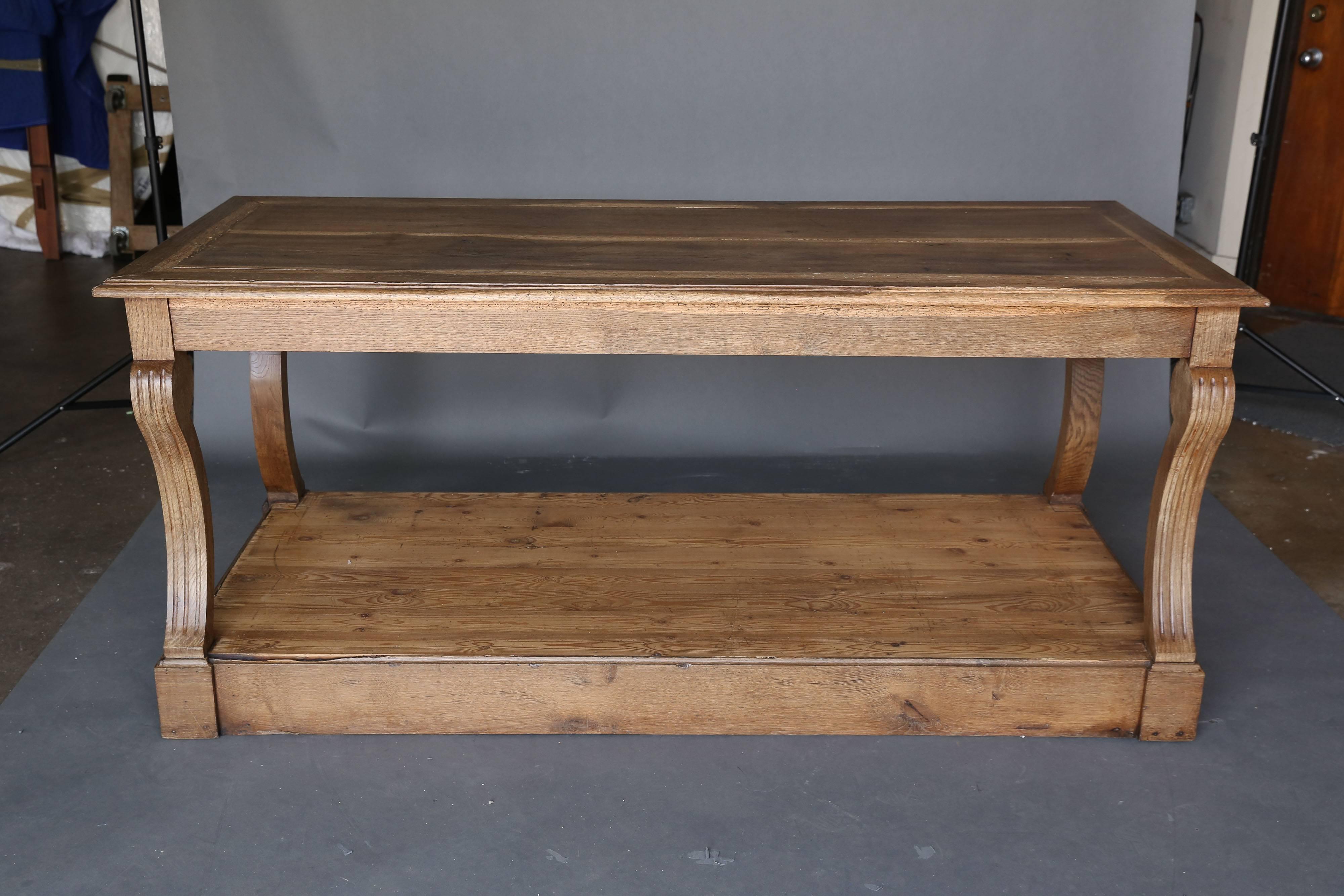 19th century oak Draper's table from a silk factory in lyon. Beautiful fluted swooping leg at all four corners and could be used as a floating table. Piece has shelf below. Wood grain on top makes it look like it is striped. This is one of a pair