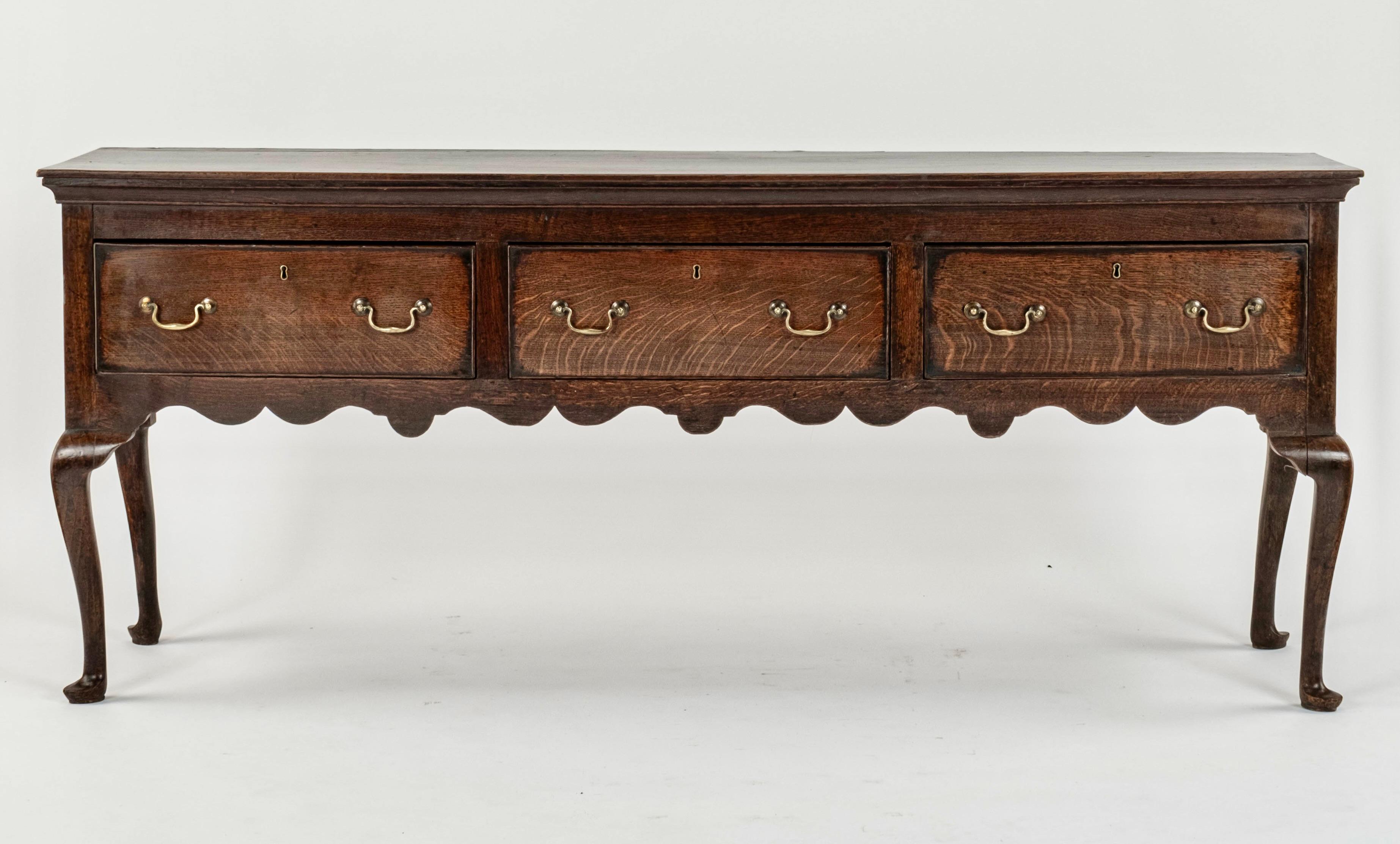 Una base per comò in rovere georgiano inglese del XVIII secolo, di ottime proporzioni, con un piano con bordi sagomati e tre cassetti profondi, con maniglie a collo di cigno in ottone e rosette in ottone. Sotto c'è un grembiule intagliato e