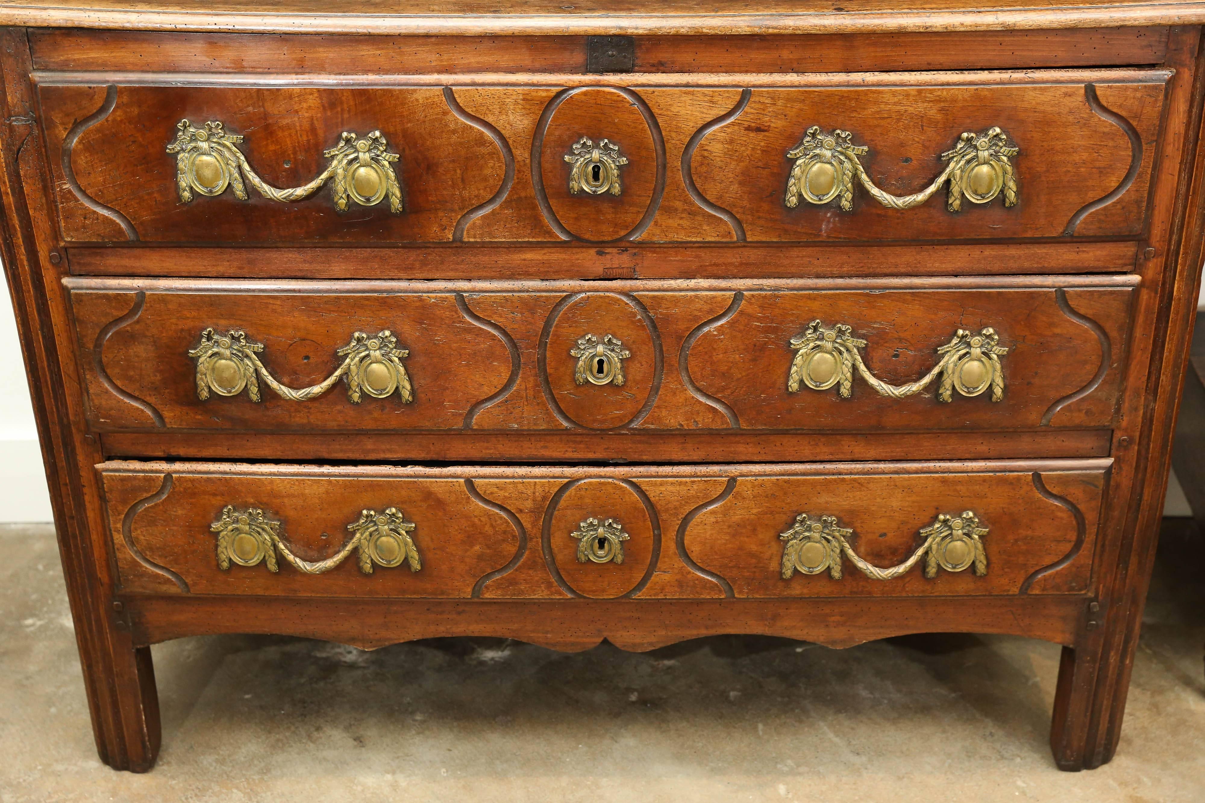 Antique 18th century Louis XV commode with three long drawers. Wood is walnut and has a beautiful patina. Hardware has been replaced with beautifully intricate bronze dore hardware and commode height has been raised.  Each drawer has deeply incised