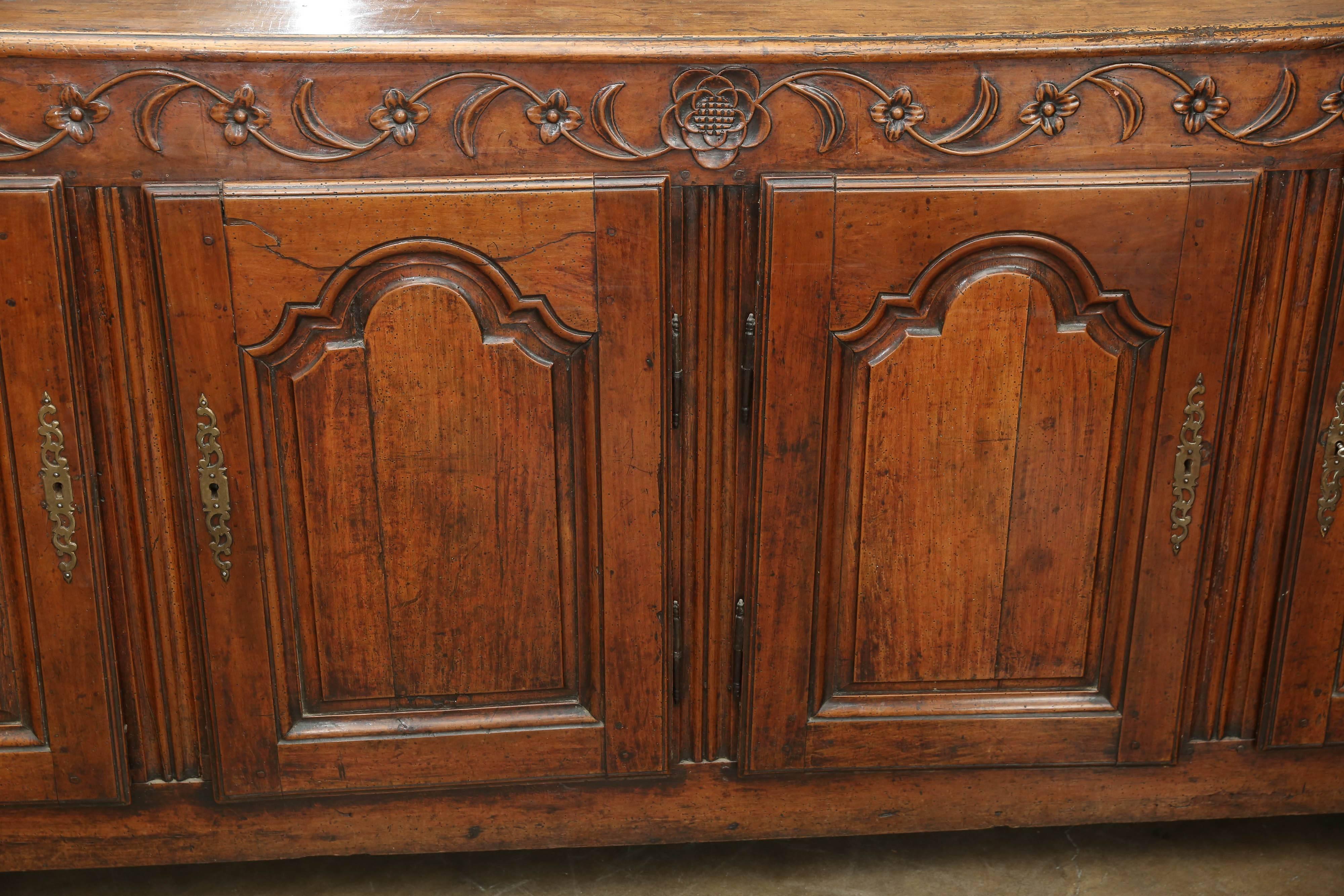 Early 19th century fruitwood buffet with four doors from France with beautifully carved trellis vine that emanates from a single multi-petal flower in the center of the piece.  The four doors are in the style of Louis XV.  The second door from the