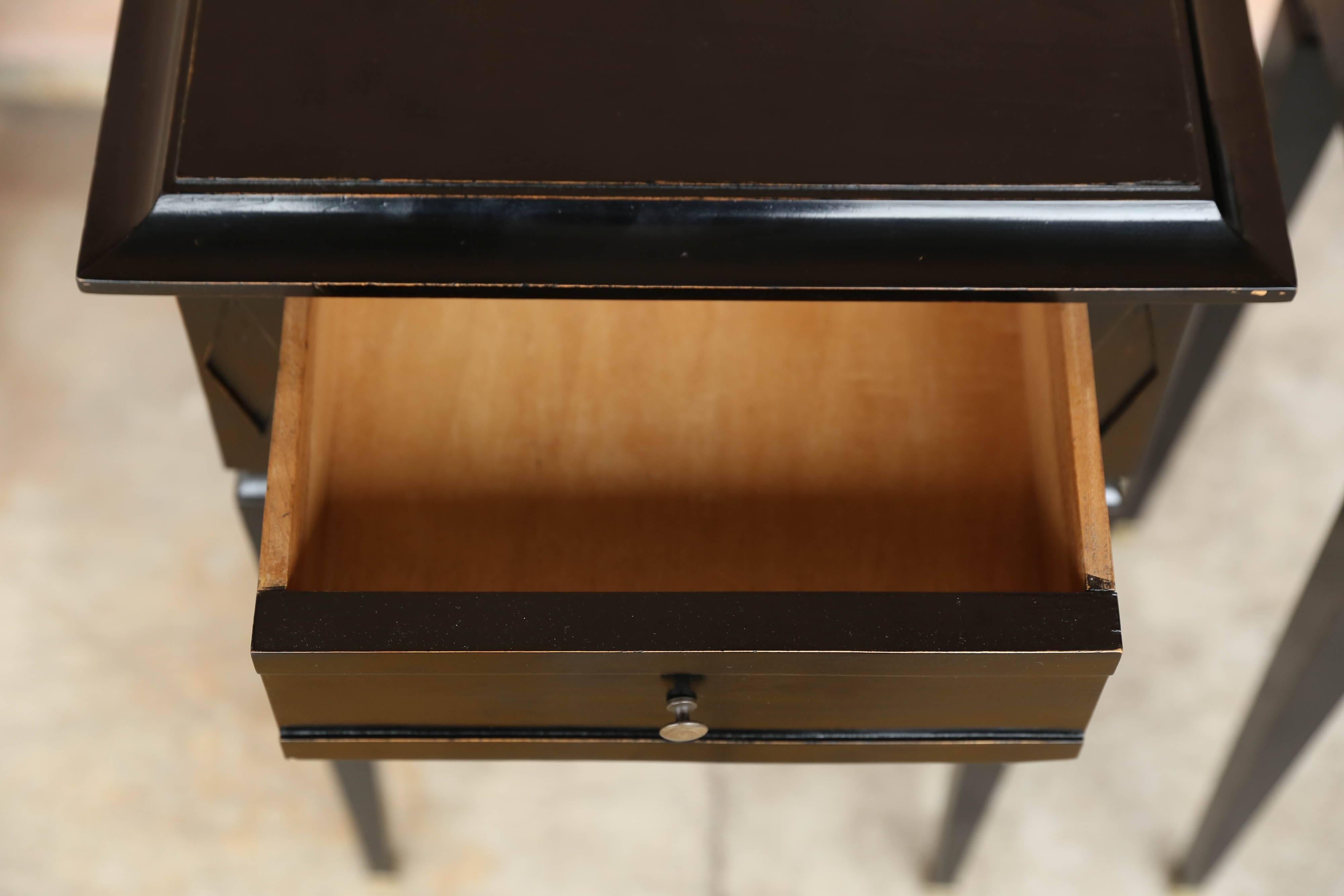 Pair of small black Federal style lacquered tables with a single drawer.  Tapered legs ending in brass capped feet.   England.