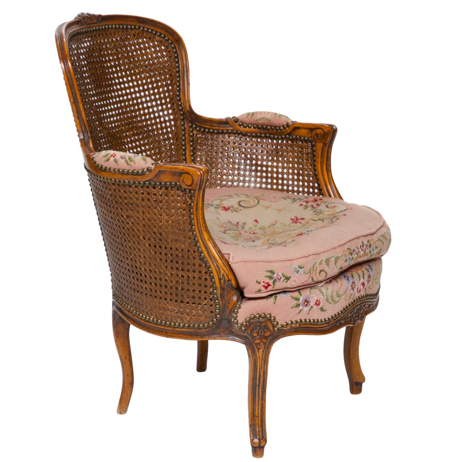 A very nice quality walnut french Louis XV bergere. The back has double cane which even curves under the arm supports. The cane is is very good condition. A nice tapestry covering to the seat and arms pads. Notice the tapestry rolls over the apron