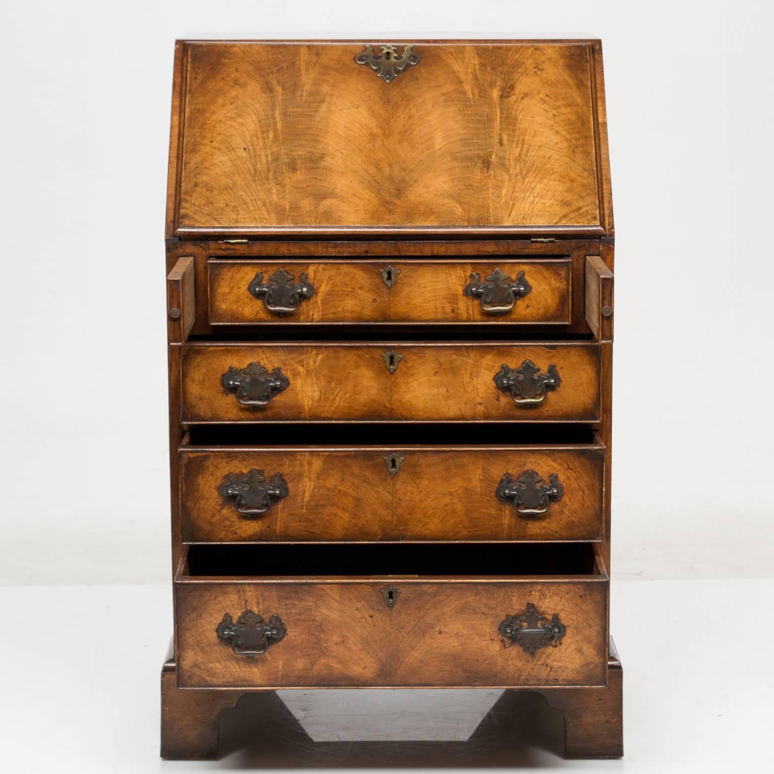 A very Queen Anne walnut slant front bureau on bracket feet. This is a versatile piece and functional size. Beautiful coloring and shading. Nice brass pulls. There is a slant front which open to reveal a fitted interior and a tooled leather inserted