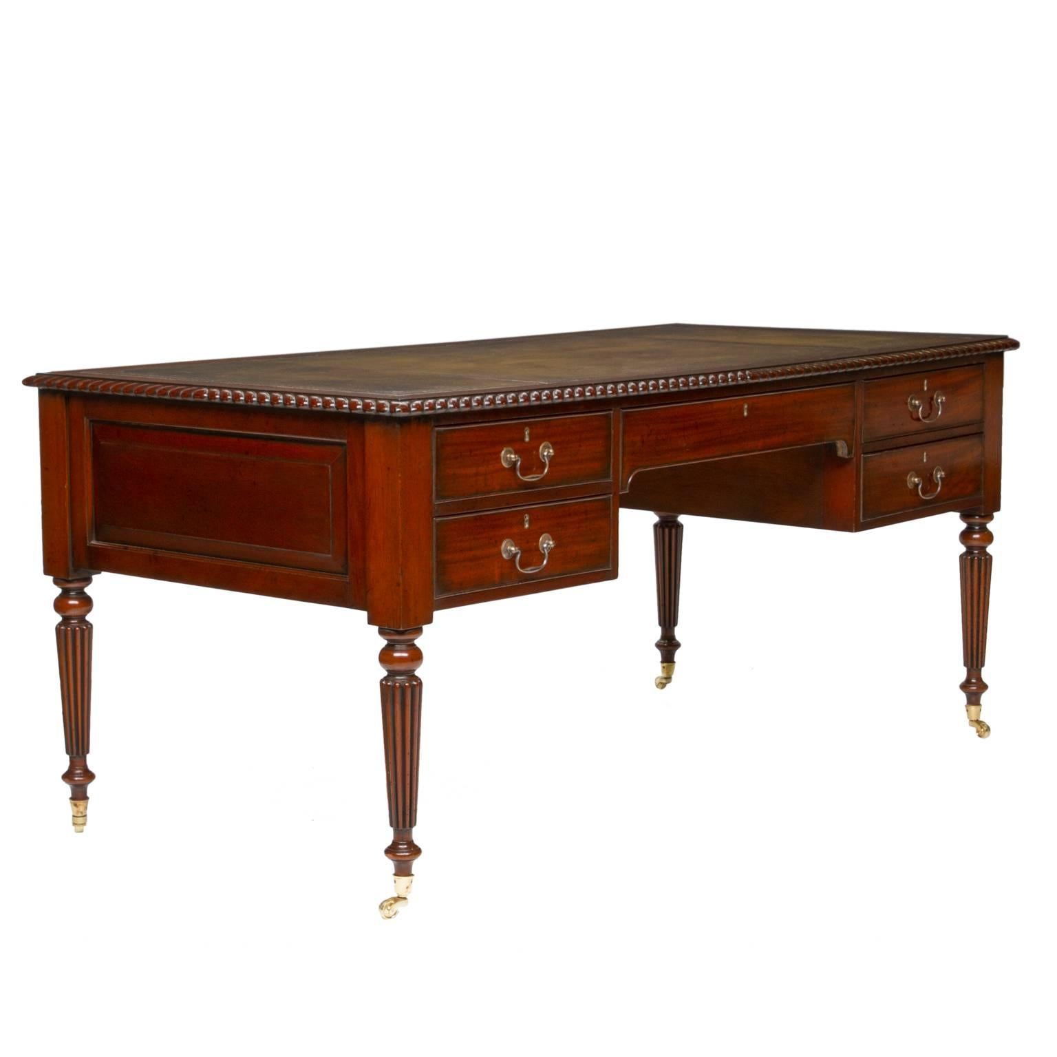 This is a handsome Regency writing desk from England. The top has a wonderful tooled leather top. The sides are raised panels from solid boards of mahogany. There is one functional side and false front side but framed to look as if it’s a partner’s