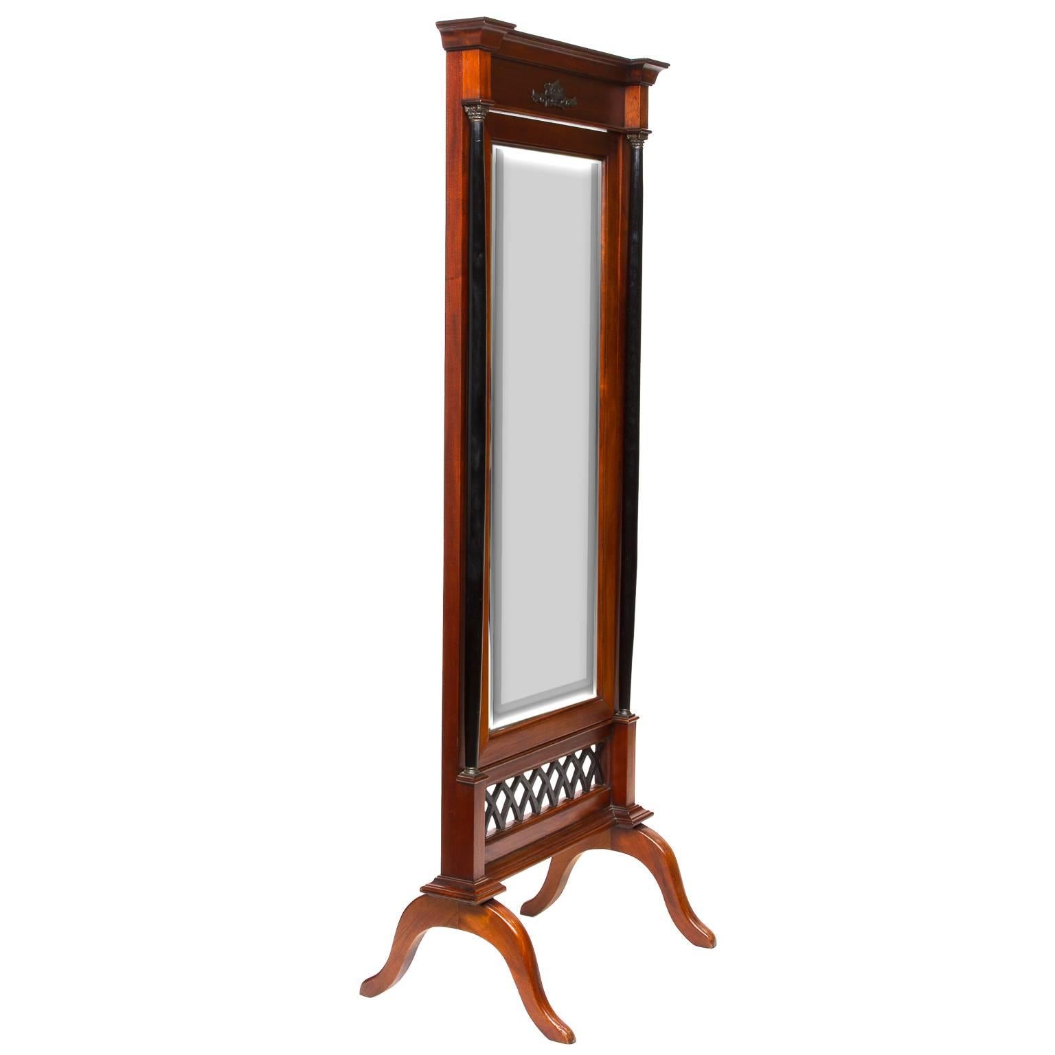 Purchased in England, is this vintage Biedermeier cheval mirror. Beveled mirror surrounded in a mahogany frame then mounted to a very supportive structure. The real look are the ebonized pair of columns to each side and the pierce design below the