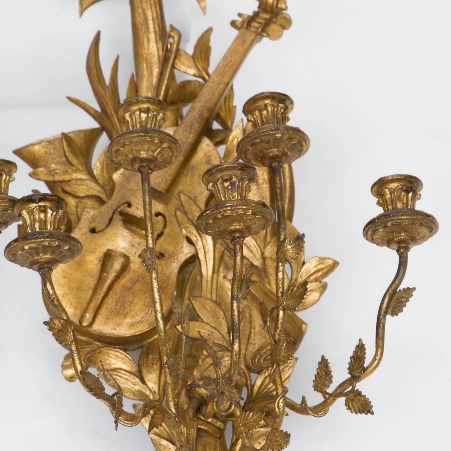 A fine pair of vintage Italian made gold leaf wall sconces. Five branch iron arms. Exceptional leaf design with musical instruments and bow topped.