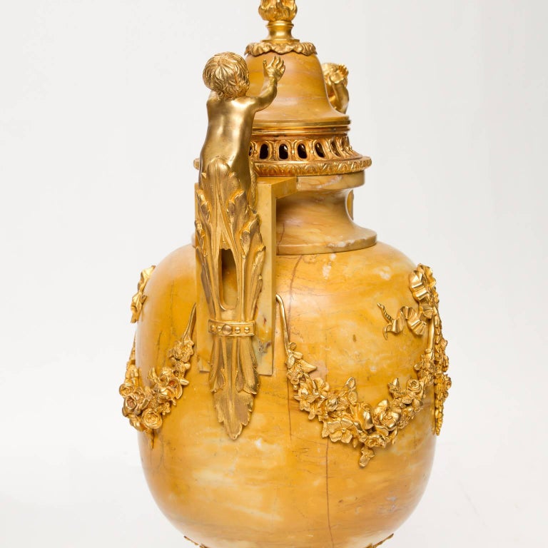 A large pair of Louis XVI style marble (Hauteville) urns with extra ordinary ormolu mounts. The mounts (excellent condition and color) supported putti's, flame tips on the caps, to the swags front and back. Above the support is a ormolu rest and