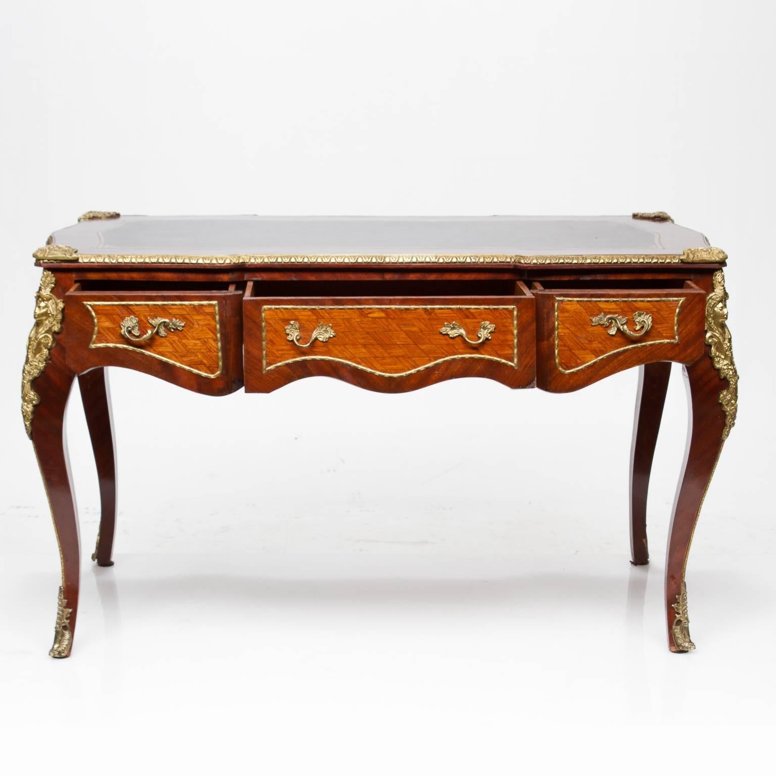 Vintage Louis XV style parquetry and straight grained inlaid bureau plat with superb bronze mounts and trims. Three functional drawers on side and false drawers to the front. Beautiful masked lady mounts to intricate bronze trim. Brown top with gold
