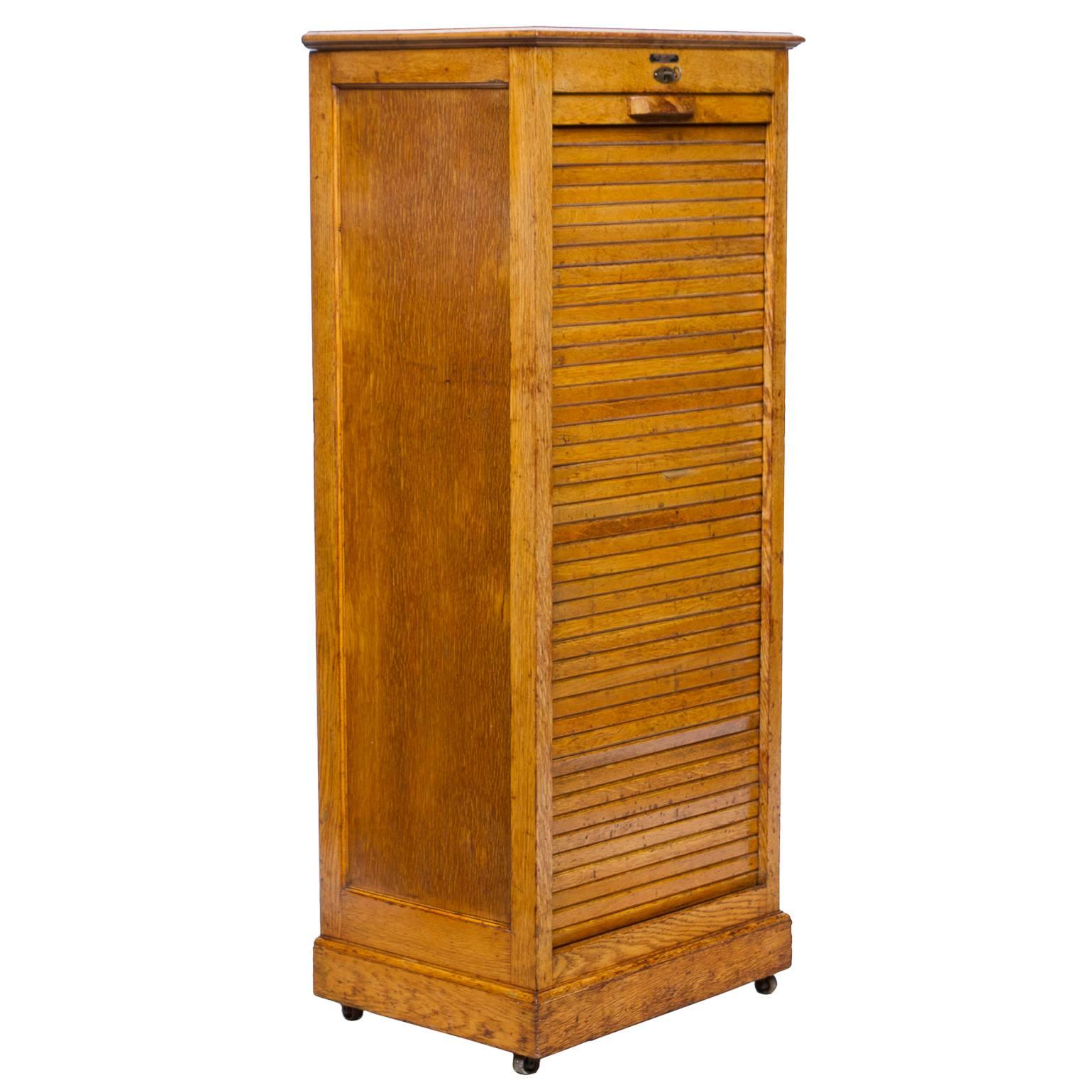 Vintage English oak file cabinet with all functional drawers and a sliding and locking tabor front with key. This piece rest upon four iron castors. Very clean piece.