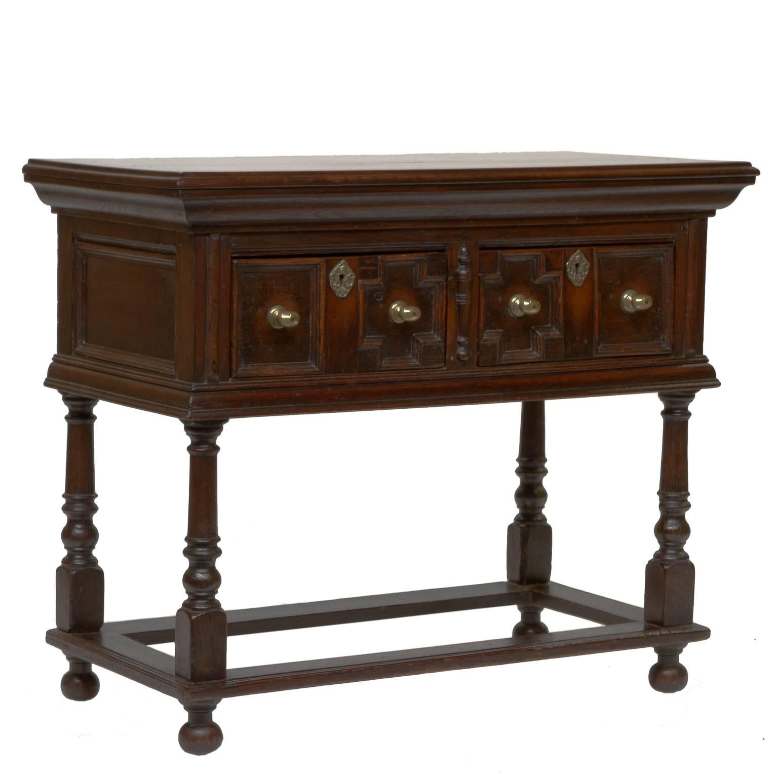 This piece is from country side of North England. This console has two drawers with brass oval pulls. Each drawers has cut pieces of oak wood, laid in patterns. Thick trim pieces. Brass eschusions center each drawer. There are four turned legs and a