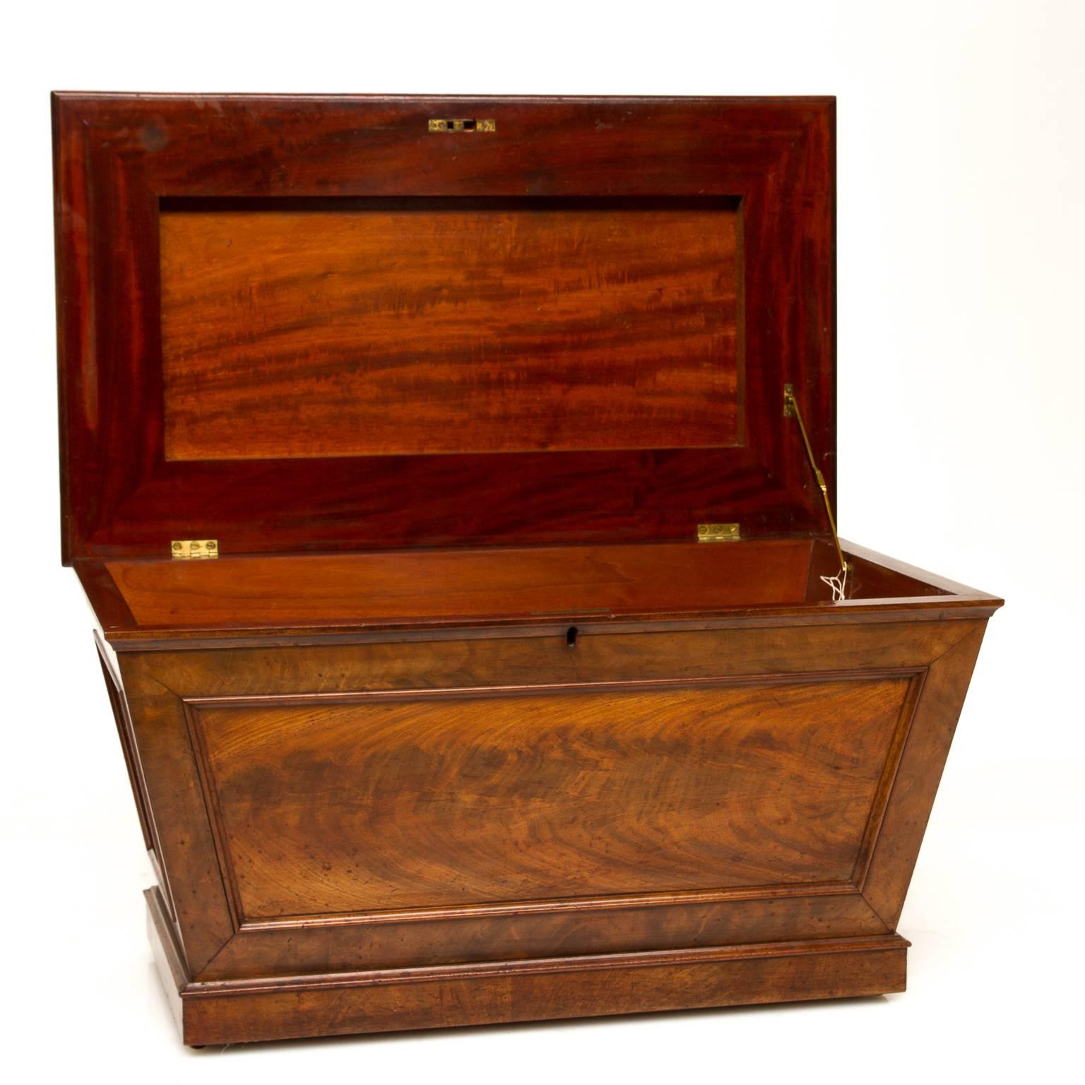 Regency mahogany Cellarette, England, early 19th century, sarcophagus-form, domed hinged lid over a shaped case with stepped base and hidden brass castors. Interior fitted with original zinc liner with dividers. Each side has recessed panel sides