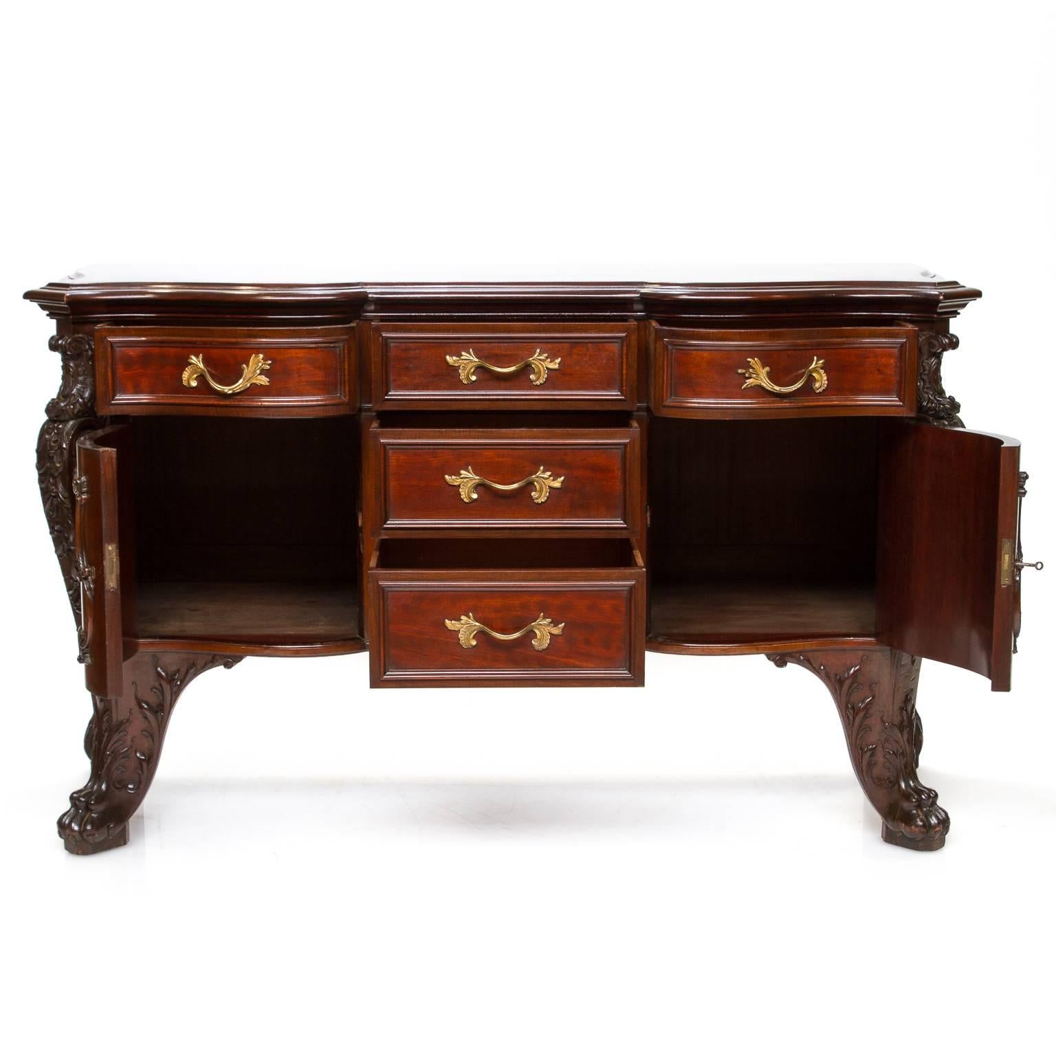 An elaborate solid mahogany commode with bombé shape and shaped front. This piece is signed 