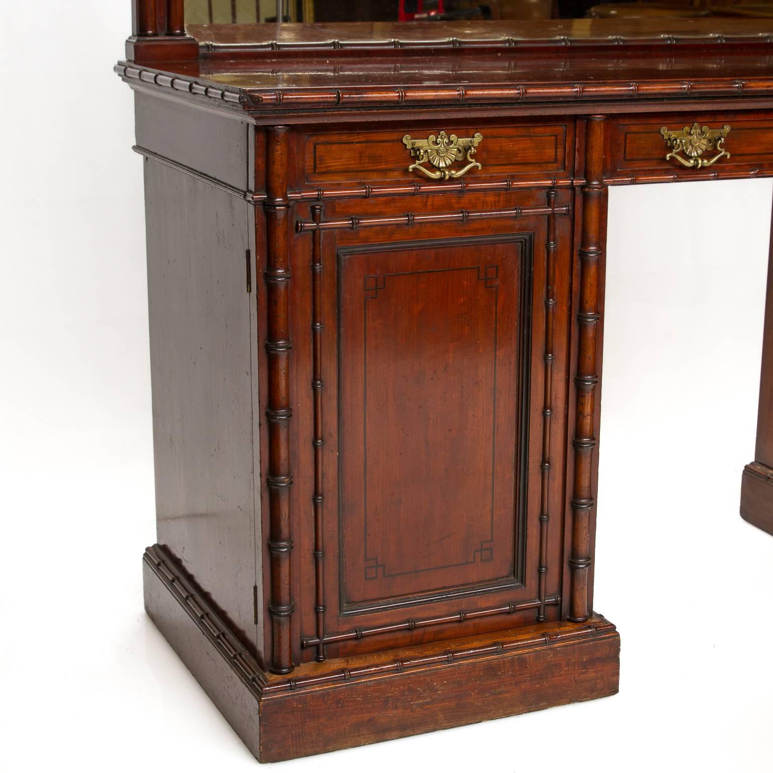 A fine English pedestal sideboard with mirror back and bamboo moldings. The sideboard is made of mahogany wood. With ebony string inlays. The mahogany is figured on the top serving area and a ribbon and straight cut to the fronts and sides. Brass