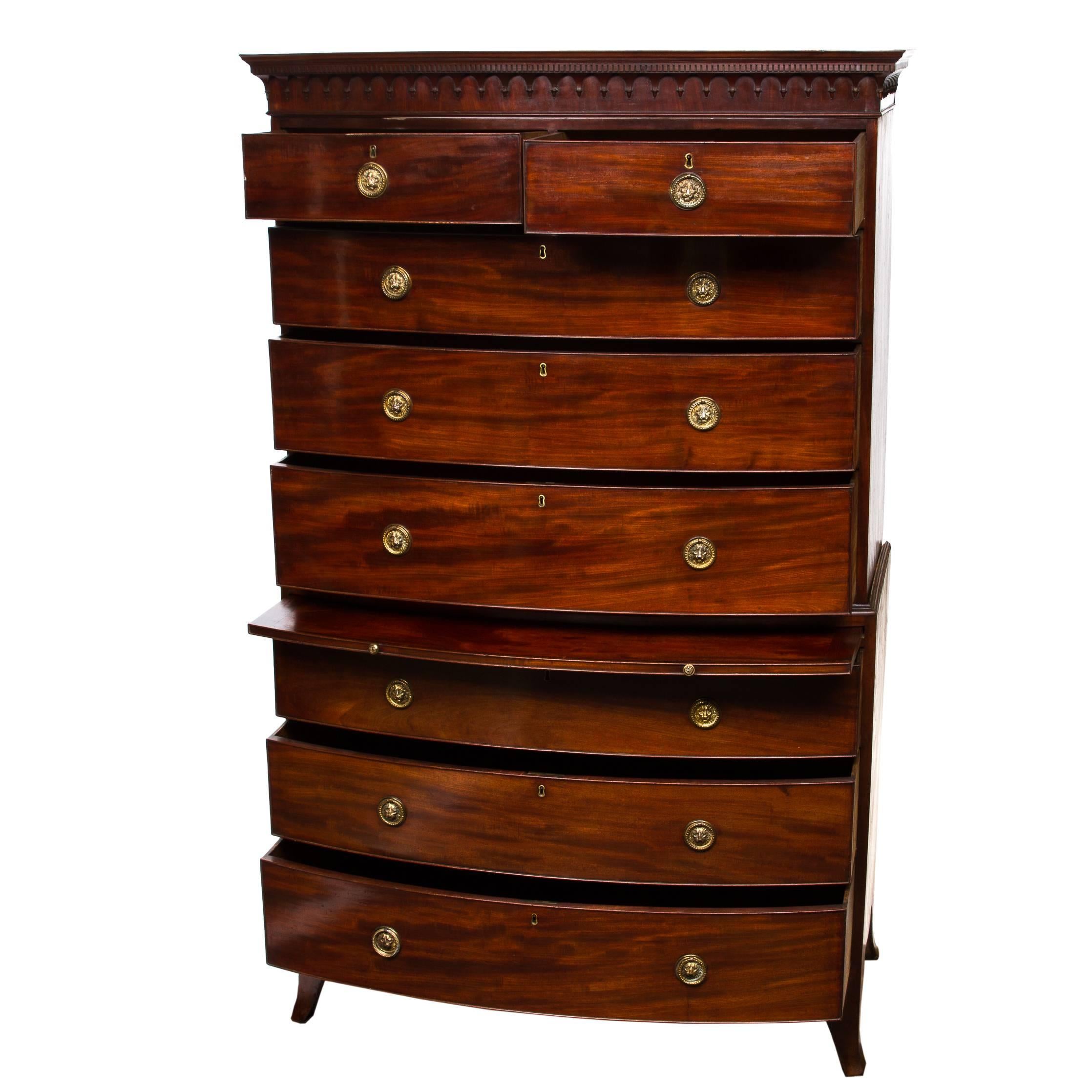 19th century English bow front three-piece chest on chest with a pull-out linen folding slide. Beautiful mahogany wood with subtle figuring. Top crown has dentil, egg and dart molding. Middle section five functional drawers, each with round brass