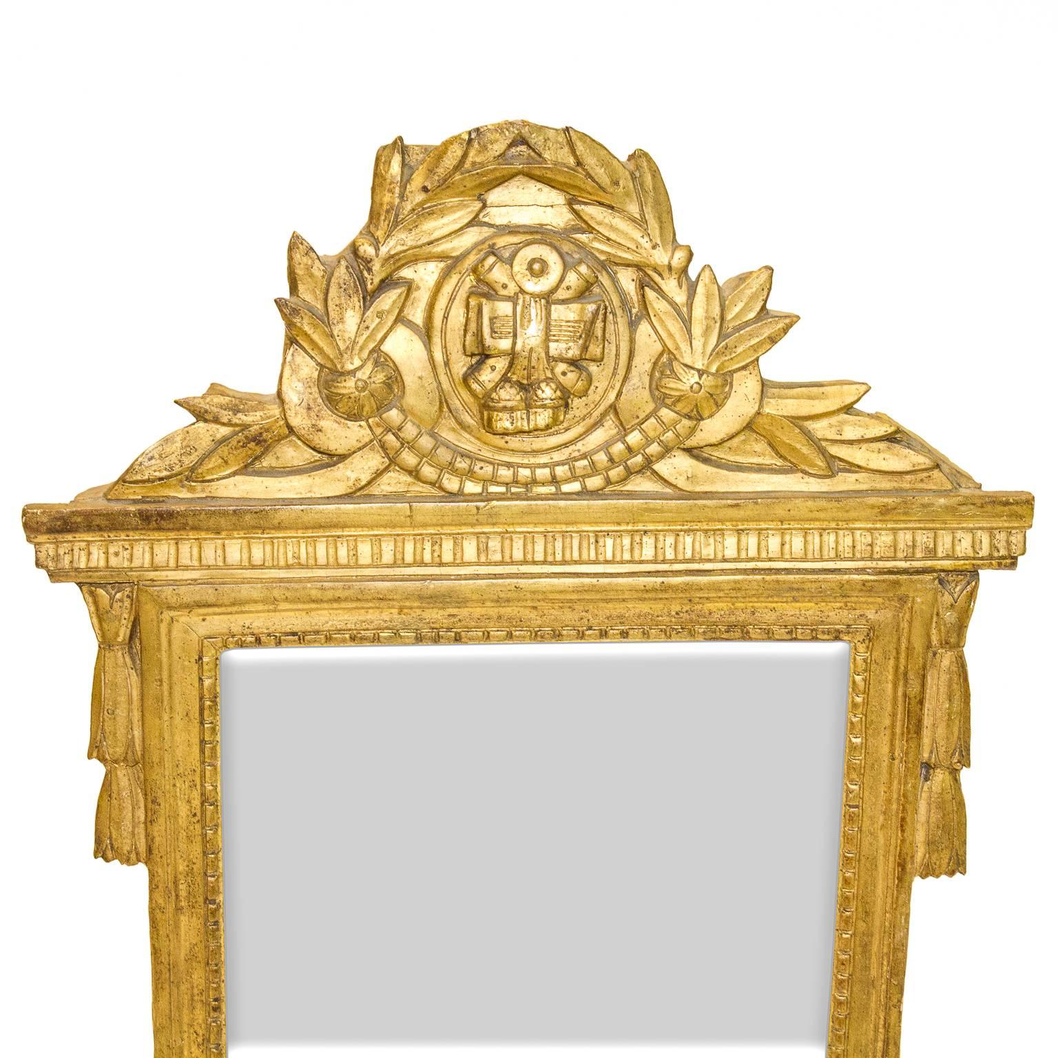 A petite Louis XVI mirror with trophy and laurel leaves carved into a giltwood frame. The mirror has the original glass, circa 1830-1840.

 

Measures: 20″ wide.

 

2.75″ deep.

 

30″ tall.

