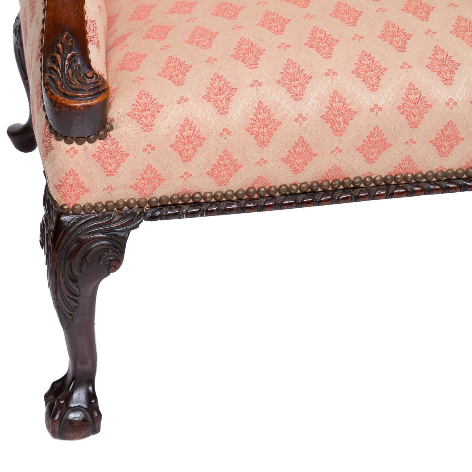 A fine George III mahogany closed arm, armchair. There is a fine fabric covering with tufting to the back and a accent pillow. The arm supports are carved with leaf design. The front two legs have a nice cabriole and acanthus leaf carved knee’s,
