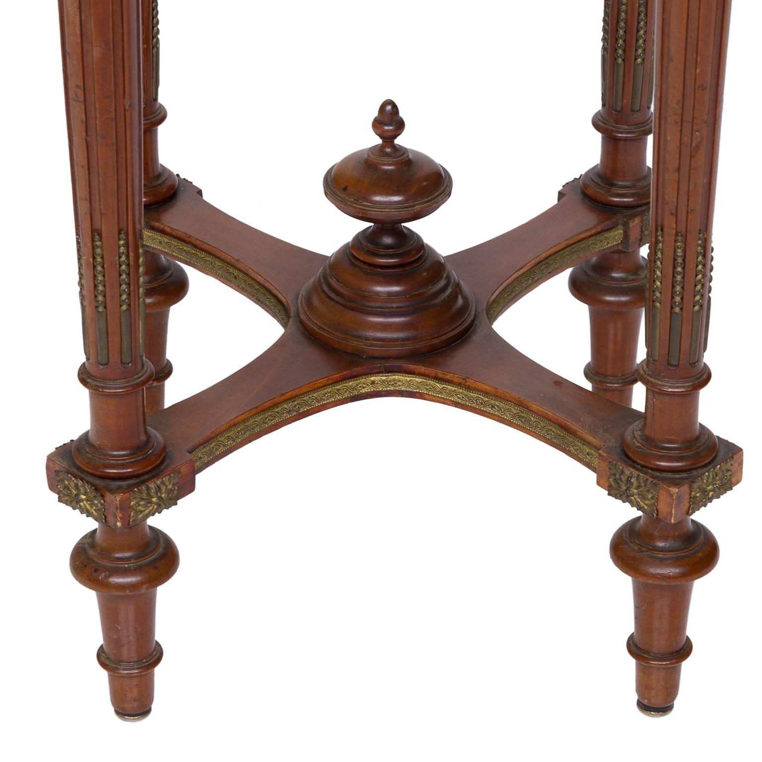 This side table is adorned with several ormolu accents, including the laurel leaf wrapped fascia molding on the apron and the swags on the tops of the legs. The tapered legs are fluted with a bead and cable inset. Decorative bronze moulding