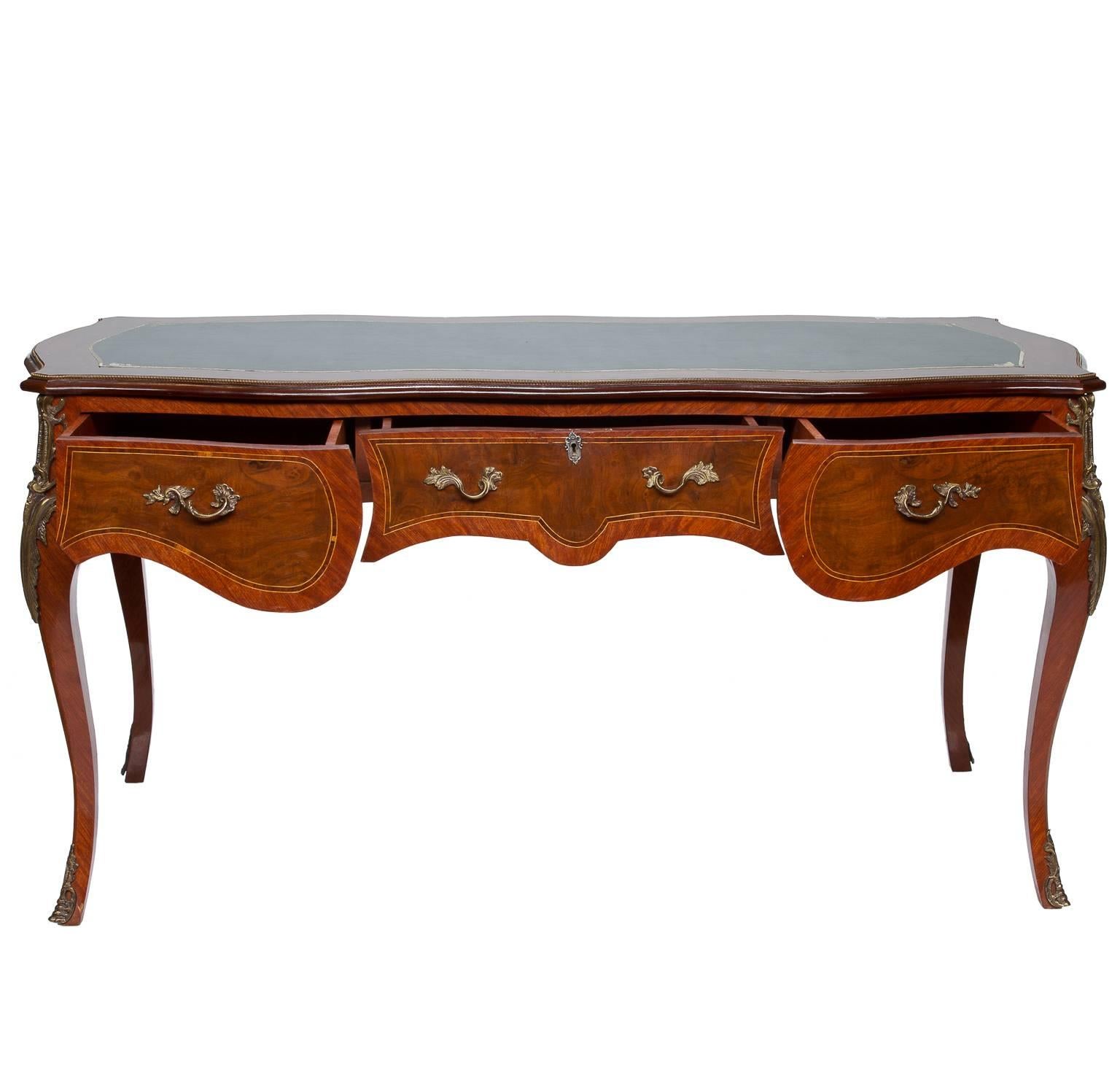 A Louis XV kingswood and burl walnut bureau plat from France. The four sides are shaped bombé style and inlaid to highlight the wood patterns. There is one fictional side with a set of three drawers. The drawers have nice ormolu Baroque handles.