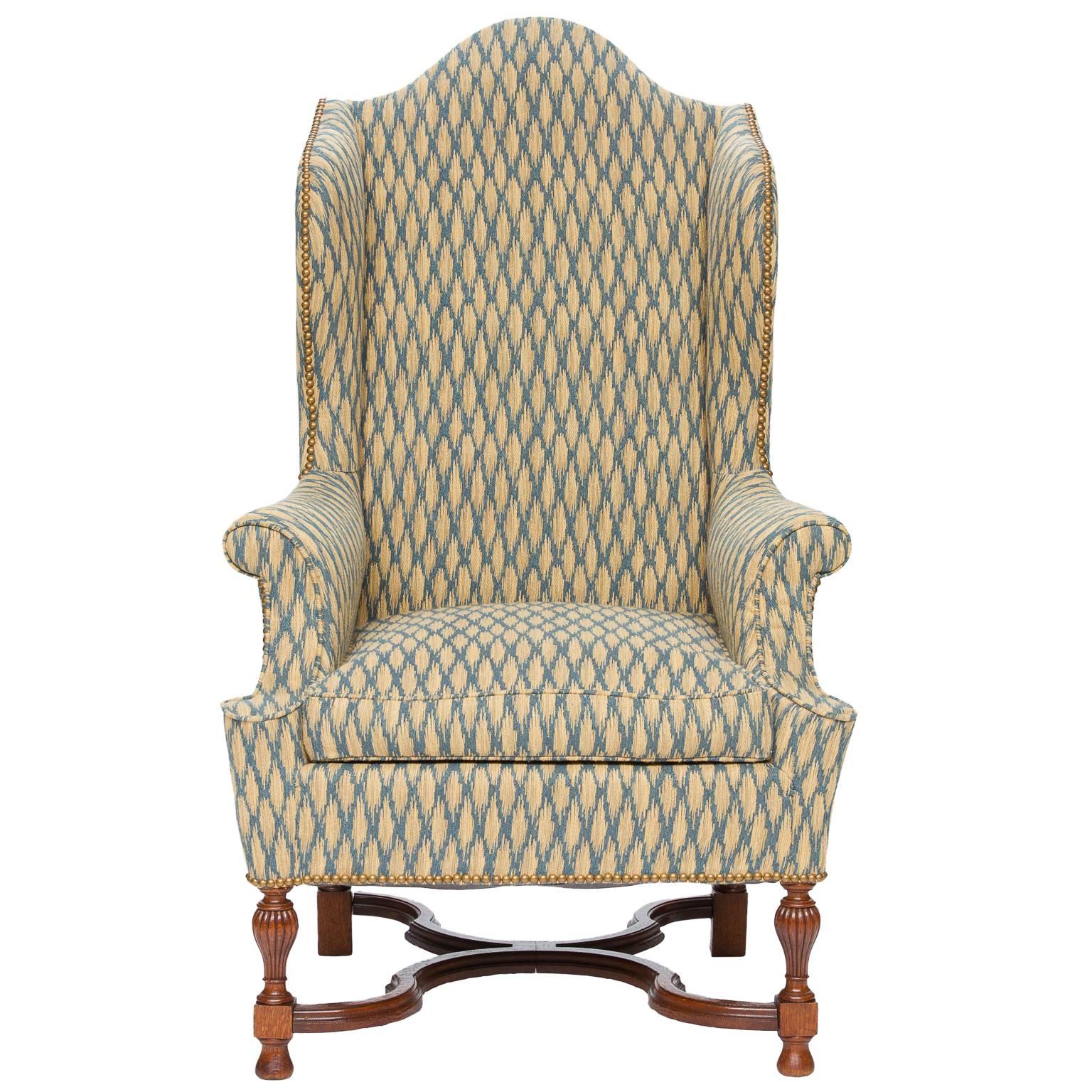 An antique reupholstered oak wingback armchair with X-stretcher and reeded cup legs. Very nice condition and a solid heavy chair. Ready for the home.