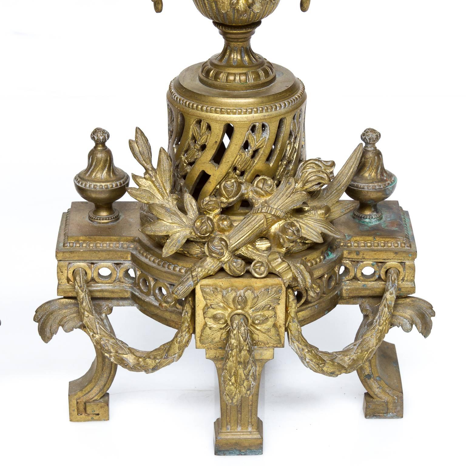 This pair of ormolu Louis XVI Chenets/firedogs. These are made from and with exceptional detail. The detail I noticed first, the trophy centered above the intricate middle leg. The swag designs connect the other legs visually. A pierced column and