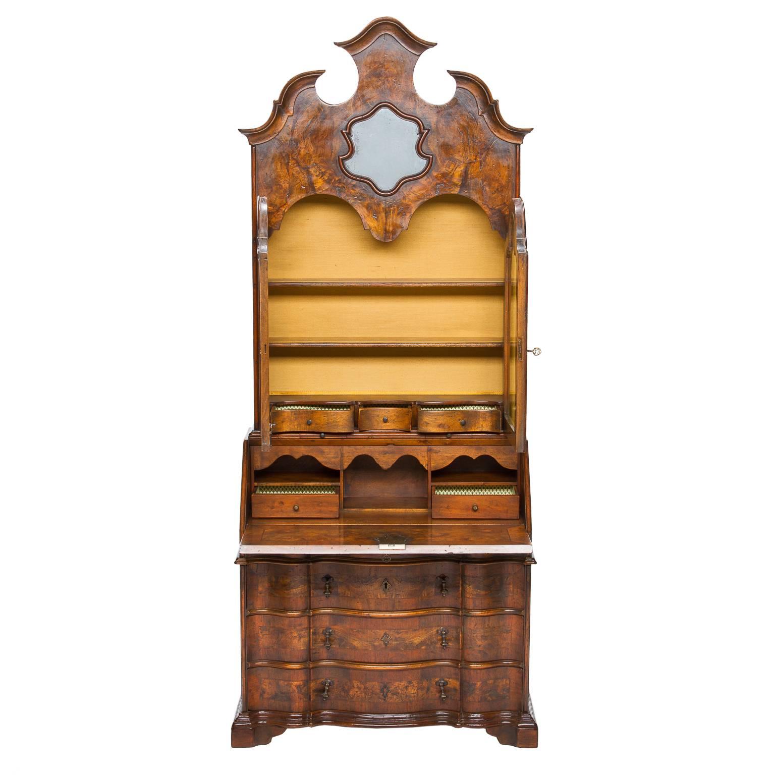 A striking Venetian burl walnut secretary. Made in the early era of the 20th century. Exceptional choices of burl walnut veneers. Two doors with beveled glass and centered above is a trumeau surrounded by a shaped crown. Lid lays open to reveal a