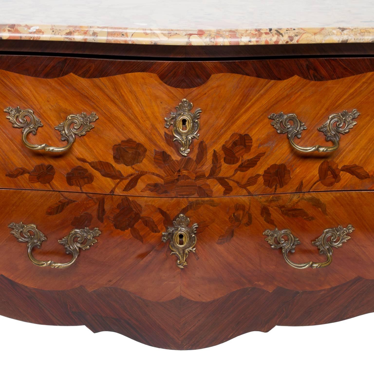 A fine Louis XV marble-top bombé inlaid commode with bronze hardware. There are two drawers and each inlaid with floral design. The commode is inlaid on each side of the commode and broken up by the shape and bronze mounts to the corners. Beautiful