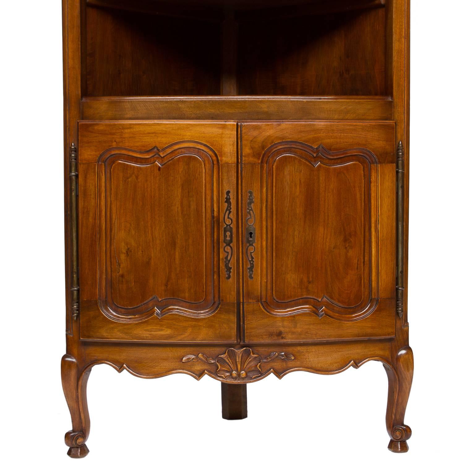 20th century provincial walnut corner cabinet.
Not real old but impressive appearance. There is a scalloped back splash on the top. One shelf and below two doors opening to storage. Scalloped apron with a carved shell. Resting on two cabriole legs
