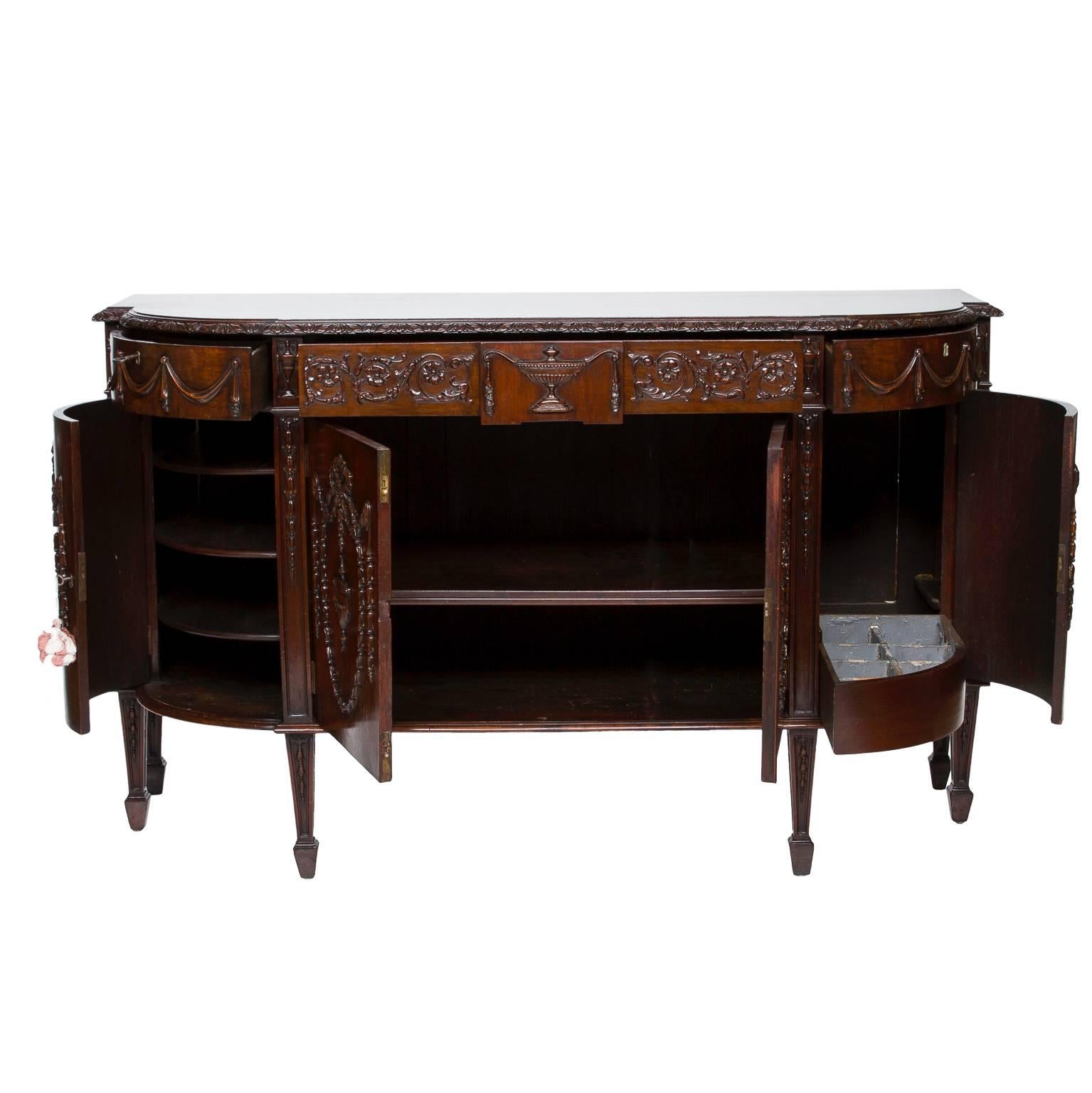 A striking 19th century Sheraton mahogany carved server with a breakfront. Rounded ends have drawers and cabinet storage. The center section to has storage behind the two carved doors. Unreal carvings adorn this server, with a french influence.