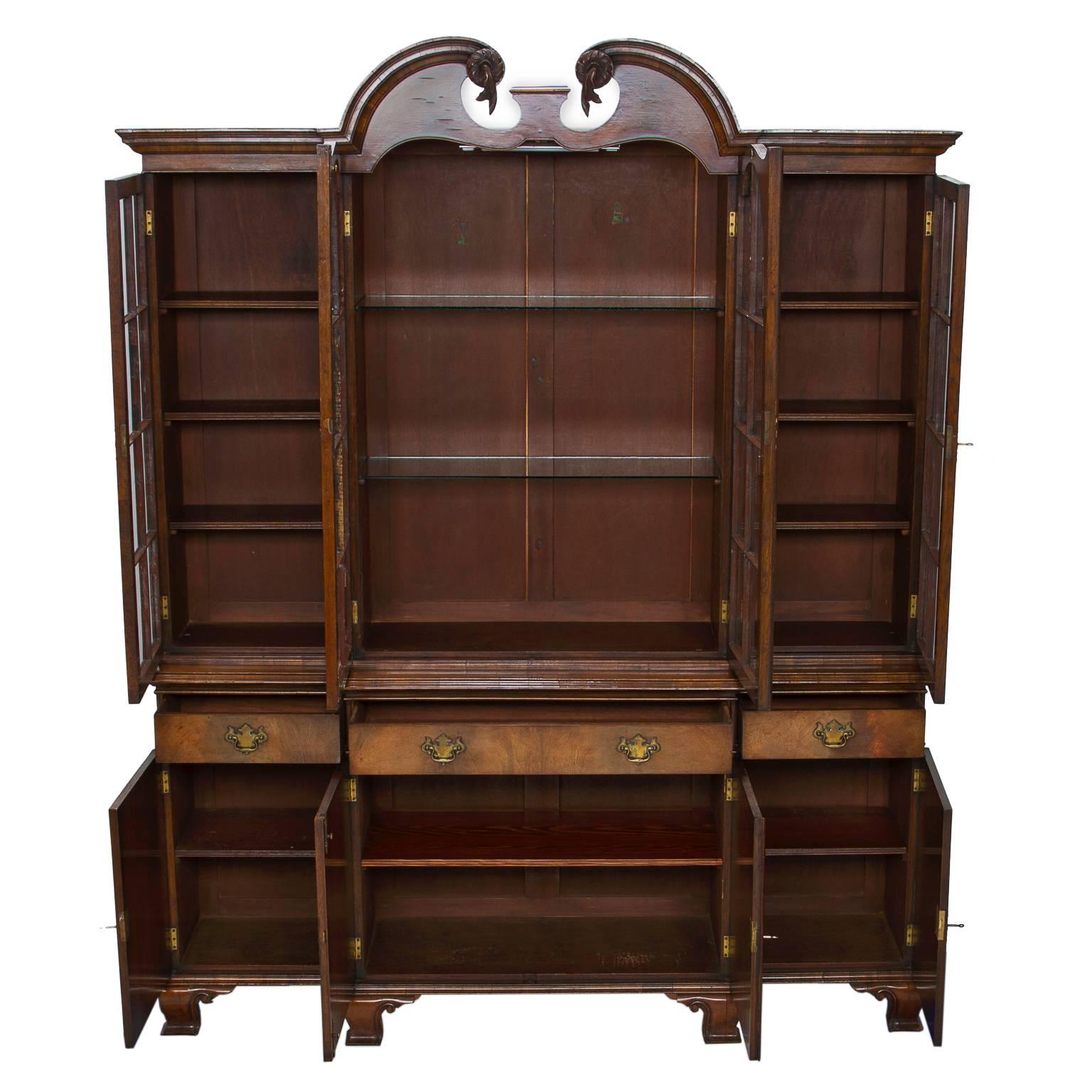 A fine English walnut breakfront with broken arch pediment. The walnut has a bleach (light appearance) look, but highlighted with the elaborate cut of the wood flaming the grain of the wood. The centre section is set forward from the sides giving it