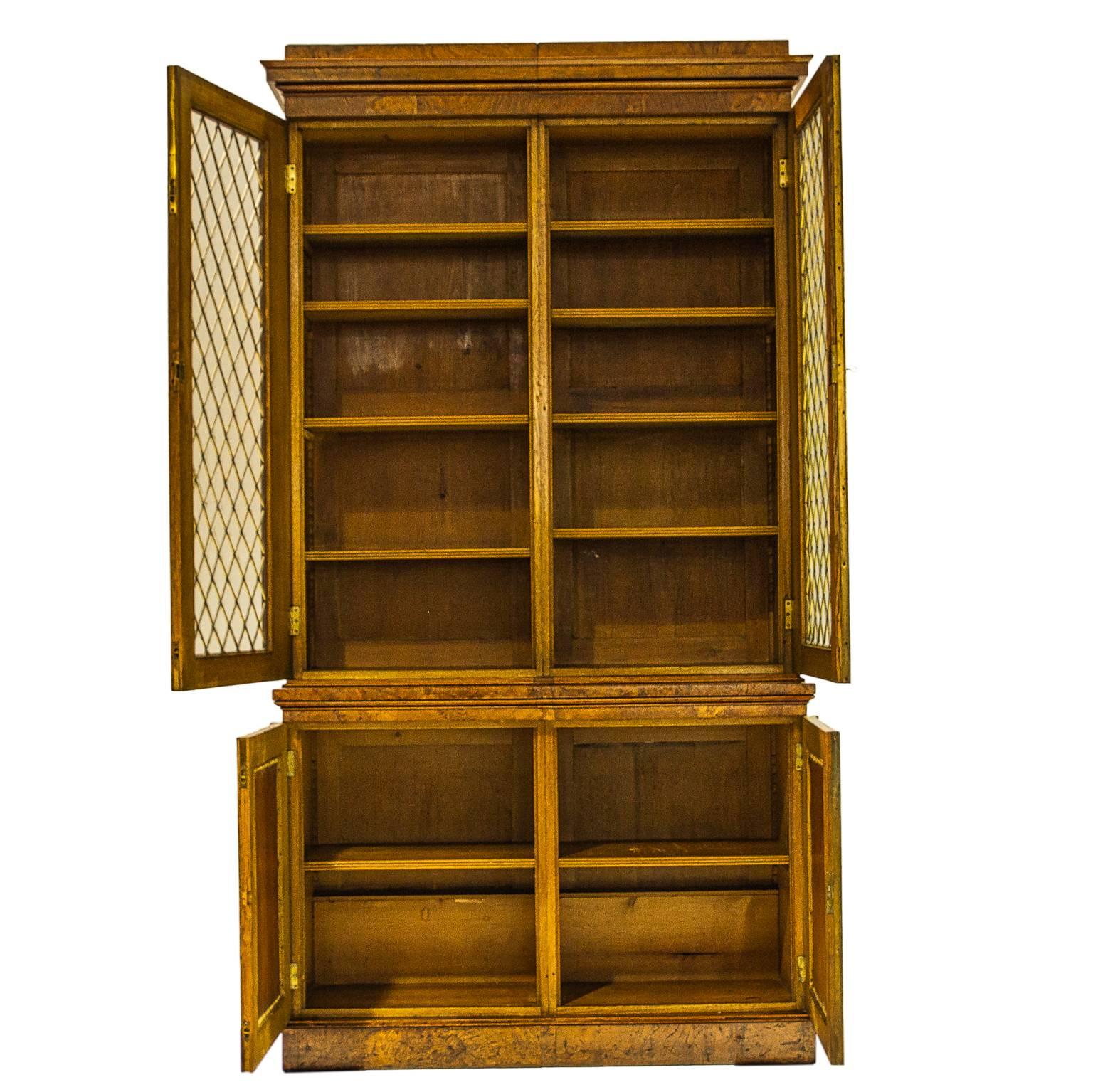19th century Regency pollard oak cabinet. Beautiful glass front bookcase/cabinet crafted in eye-catching pippy oak veneer. Lower cabinet features exquisite fabric panels under the brass mesh to provide discreet storage of your items. Brass hardware,