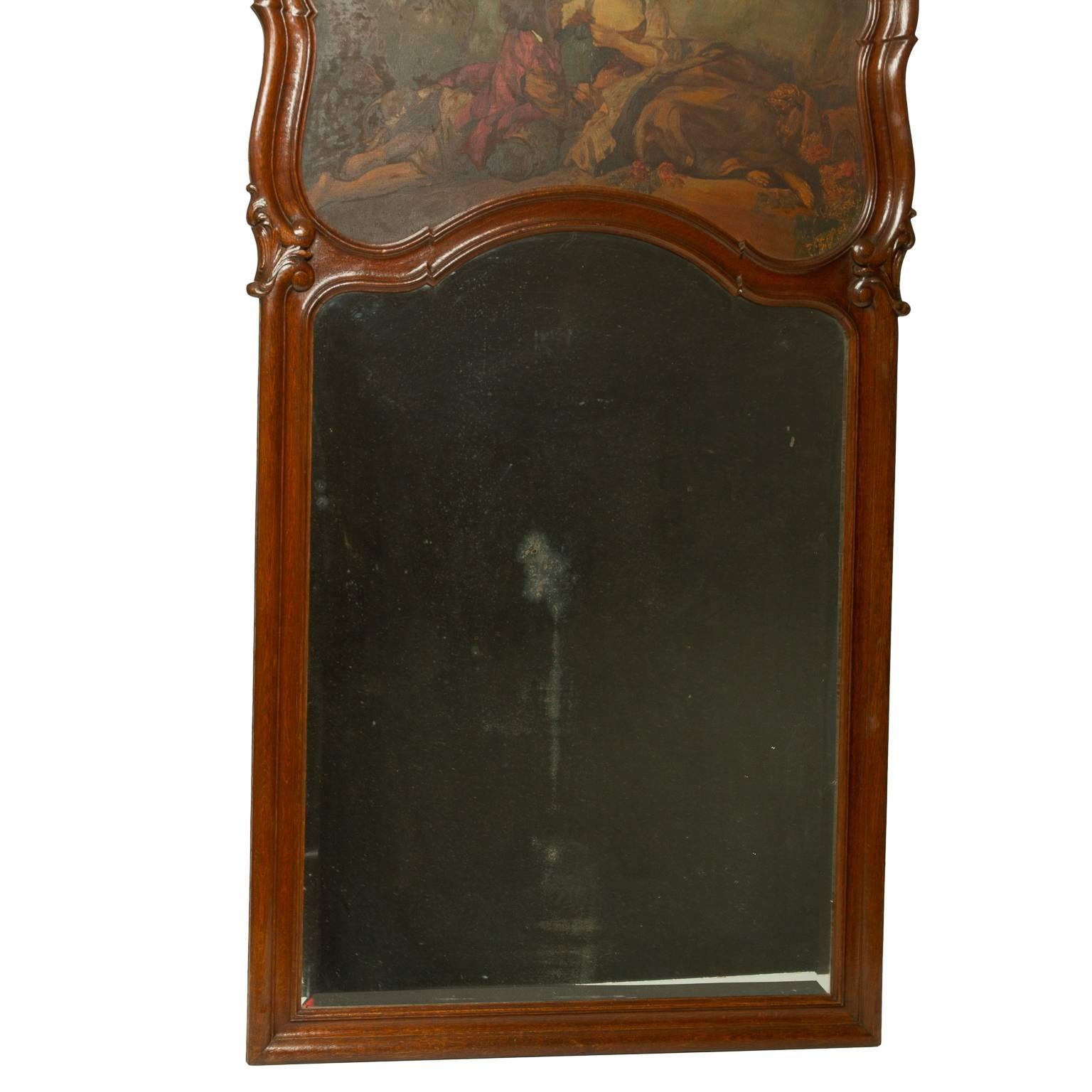 A superb Louis XV style French oak trumeau mirror. The oil on canvas painting of a couple in a garden is surrounded by a shaped frame leading to an elaborate crest which has a shell carving surrounded by floral and leaf carvings. There is a bevelled