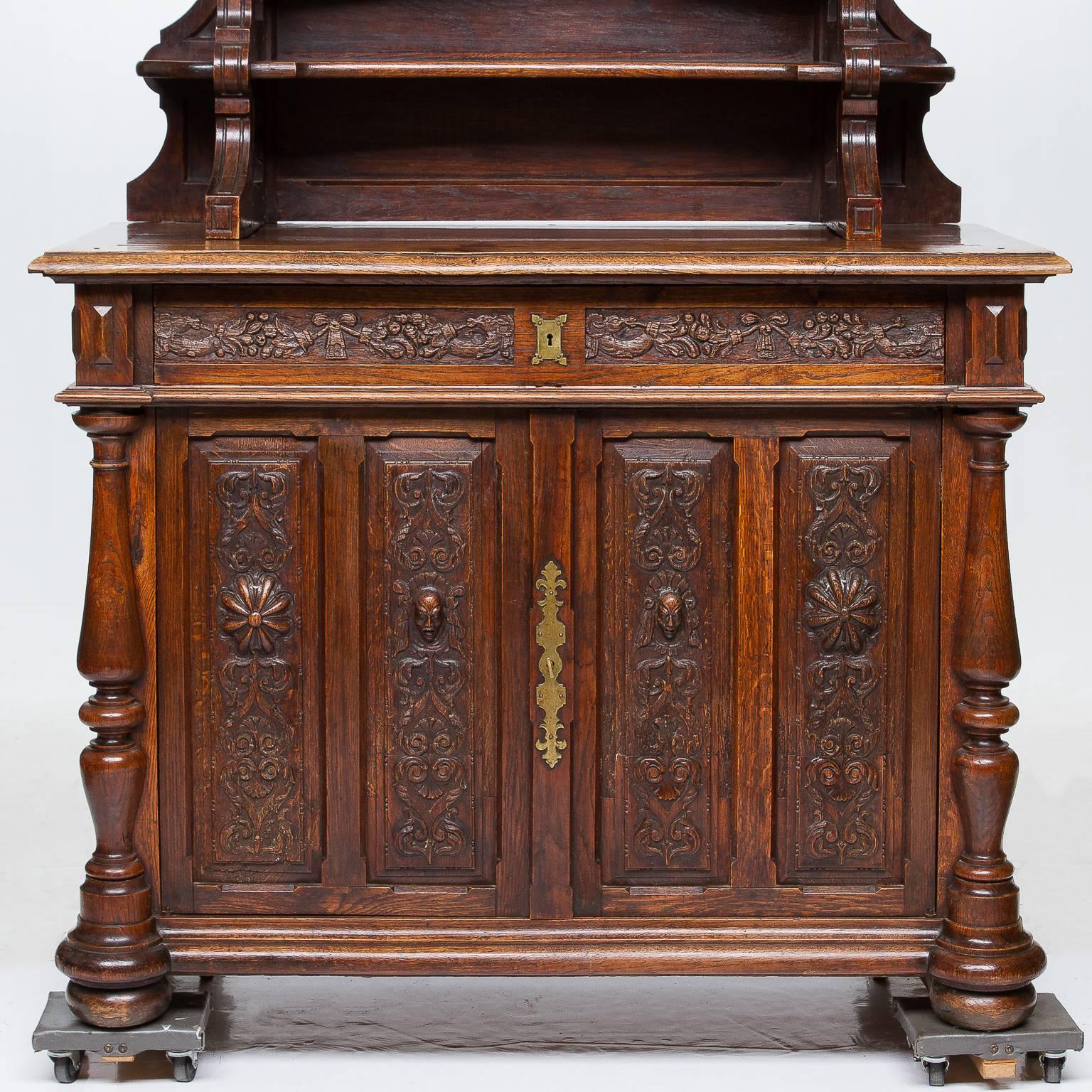 A stunning French oak vaisselier from the 19th century. Beautiful buffet base, intricately carved on raised panels. Large turned columns on the corners. Two doors open to reveal cabinet. One long single drawer above doors. The top section very