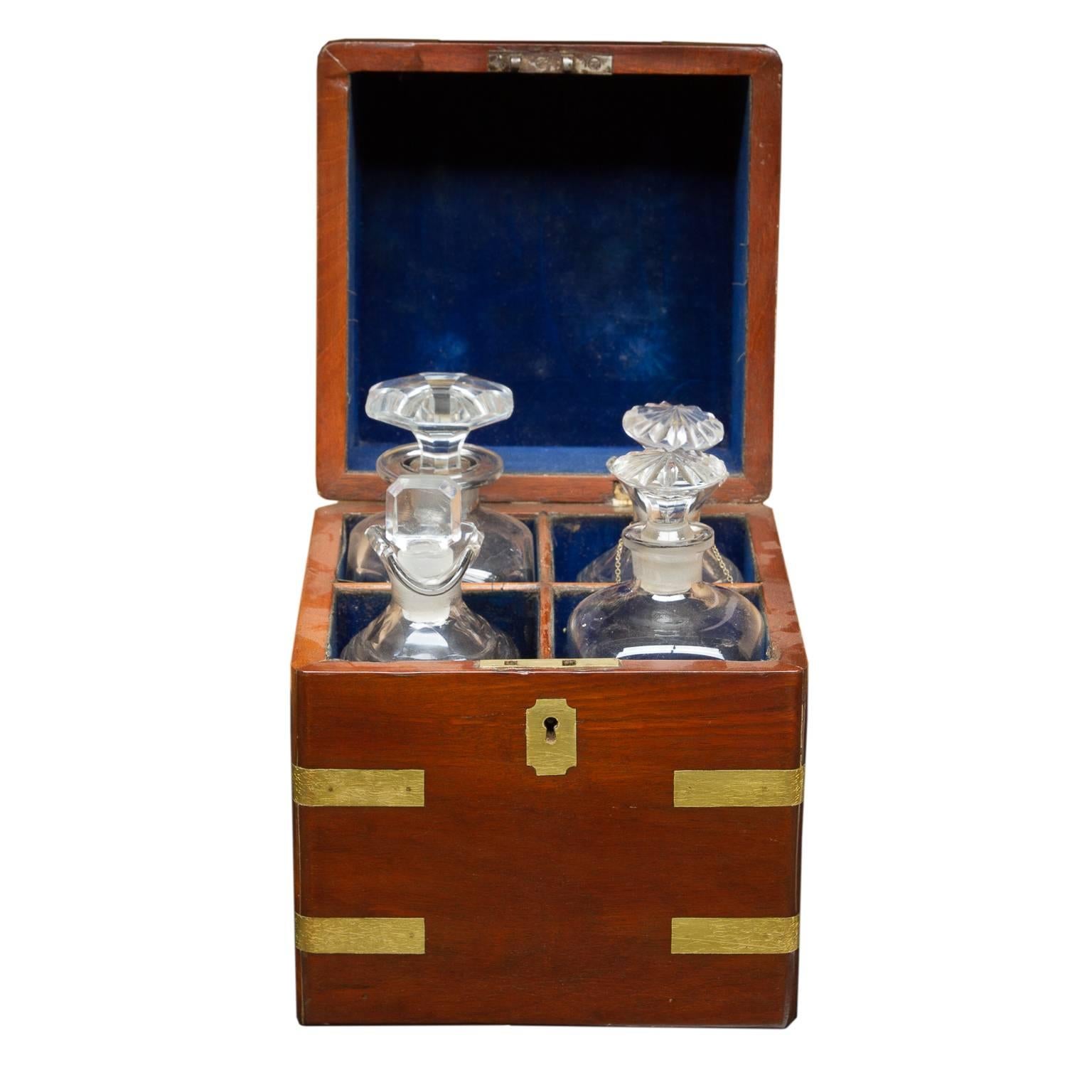 A striking English mahogany Campaign decanter box with four bottles. Fine brass work is applied to the box, giving the Campaign style look. Corners wrapped with shaped brass. Nice plaque adorns the top and the keyhole. Opened reveals four not