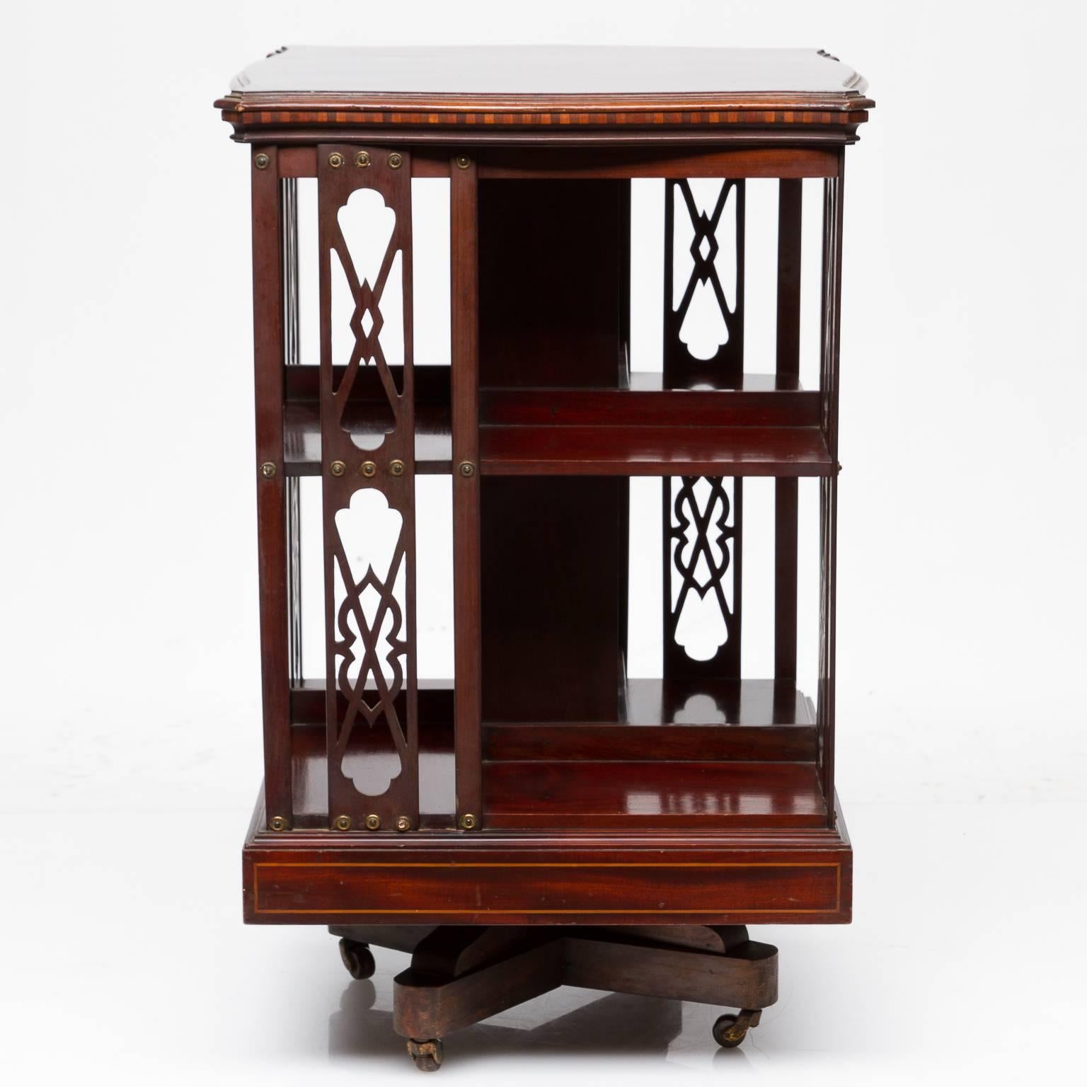 A fine inlaid mahogany revolving bookstand. Inlaid top, and trim around the top, pierced work on sides and finished shelves. This rest upon a sturdy base which revolves and castors for mobility. Very nice quality piece. Signed 