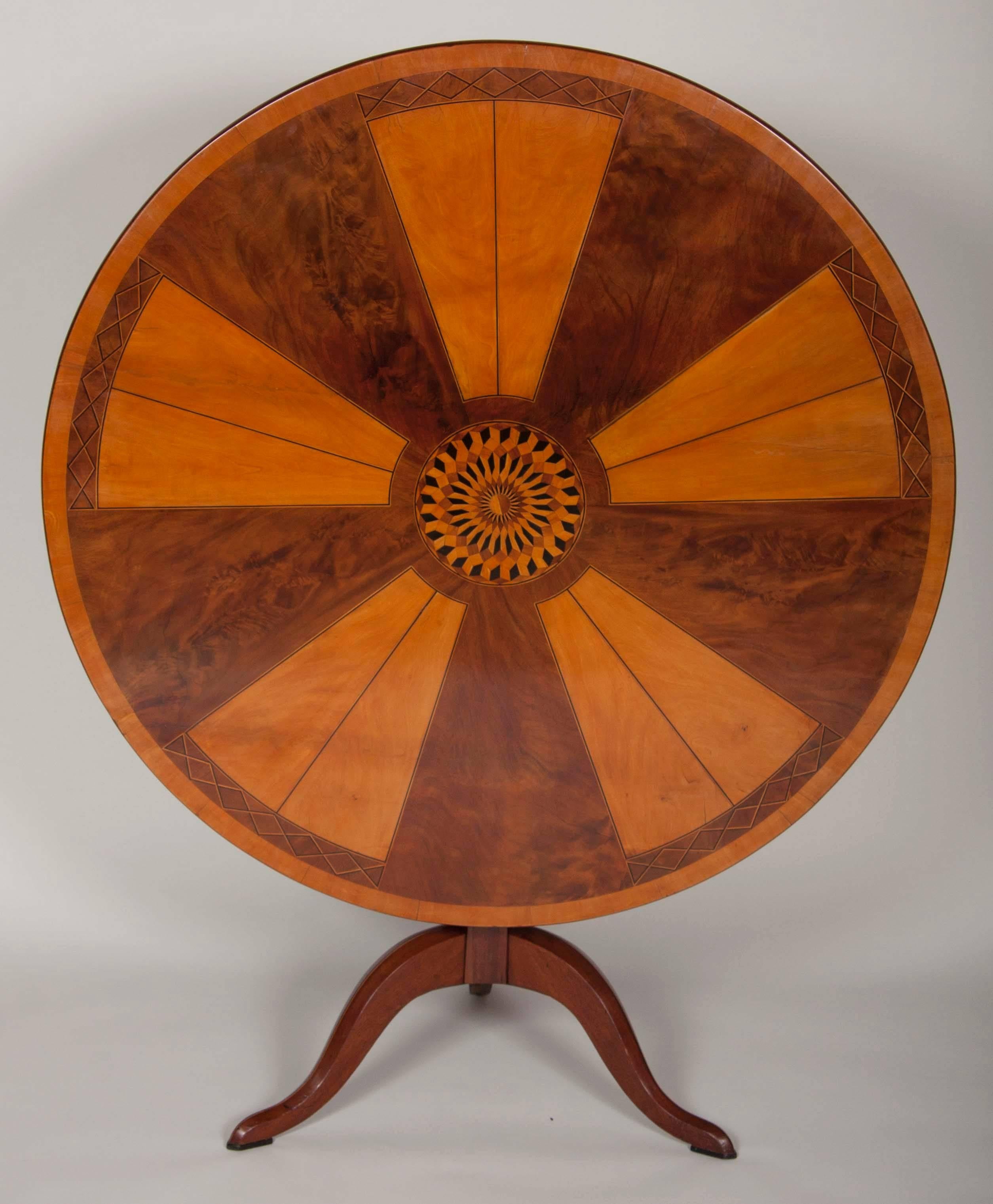 A beautiful Italian round tilt-top table with exceptional marquetry work. Marquetry woods include quilted mahogany, ebony and fruitwood.