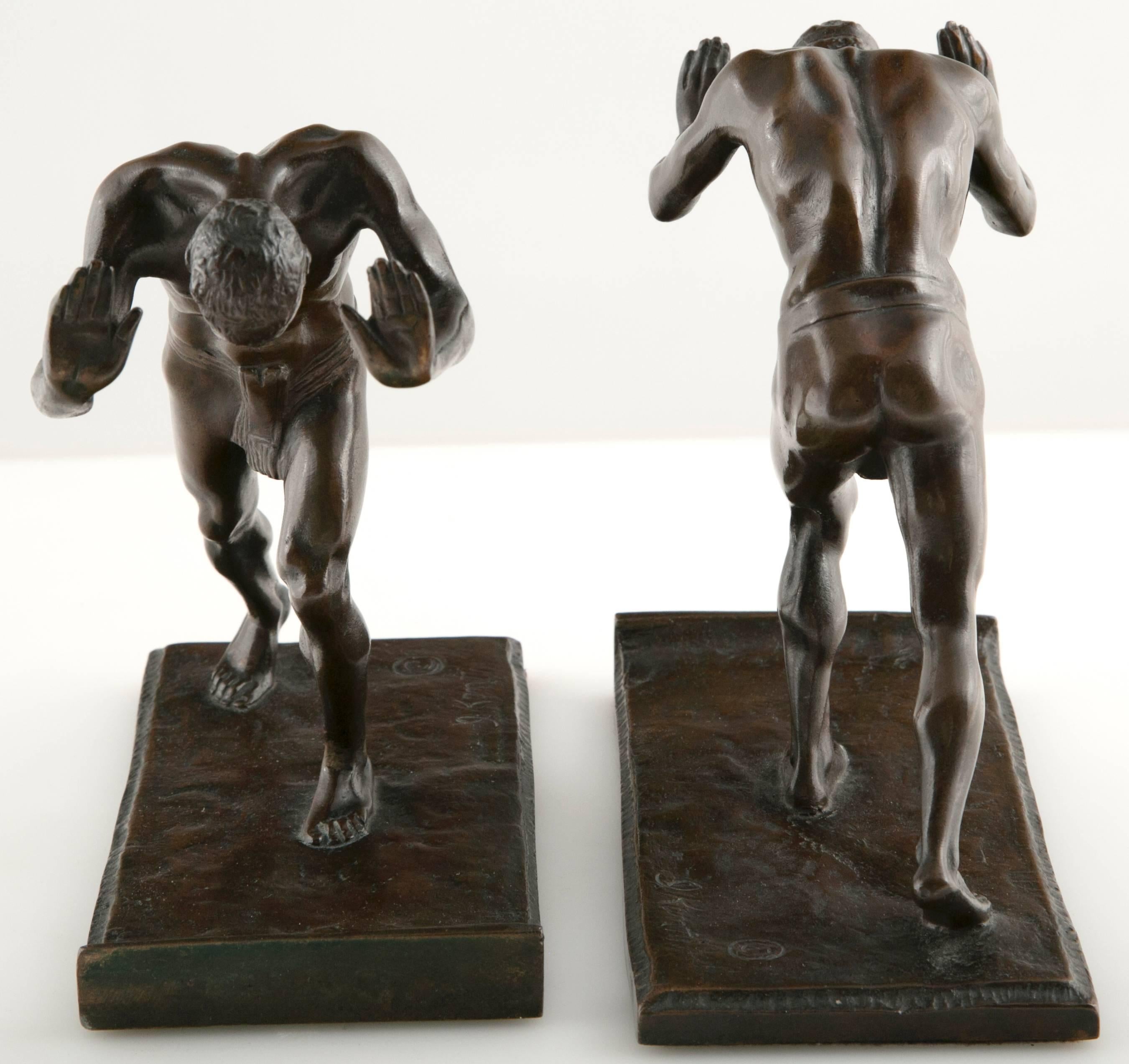 A pair of bronze Art Deco bookends by Isidore Konti in the form of muscular men. Gorham Co. Foundry.